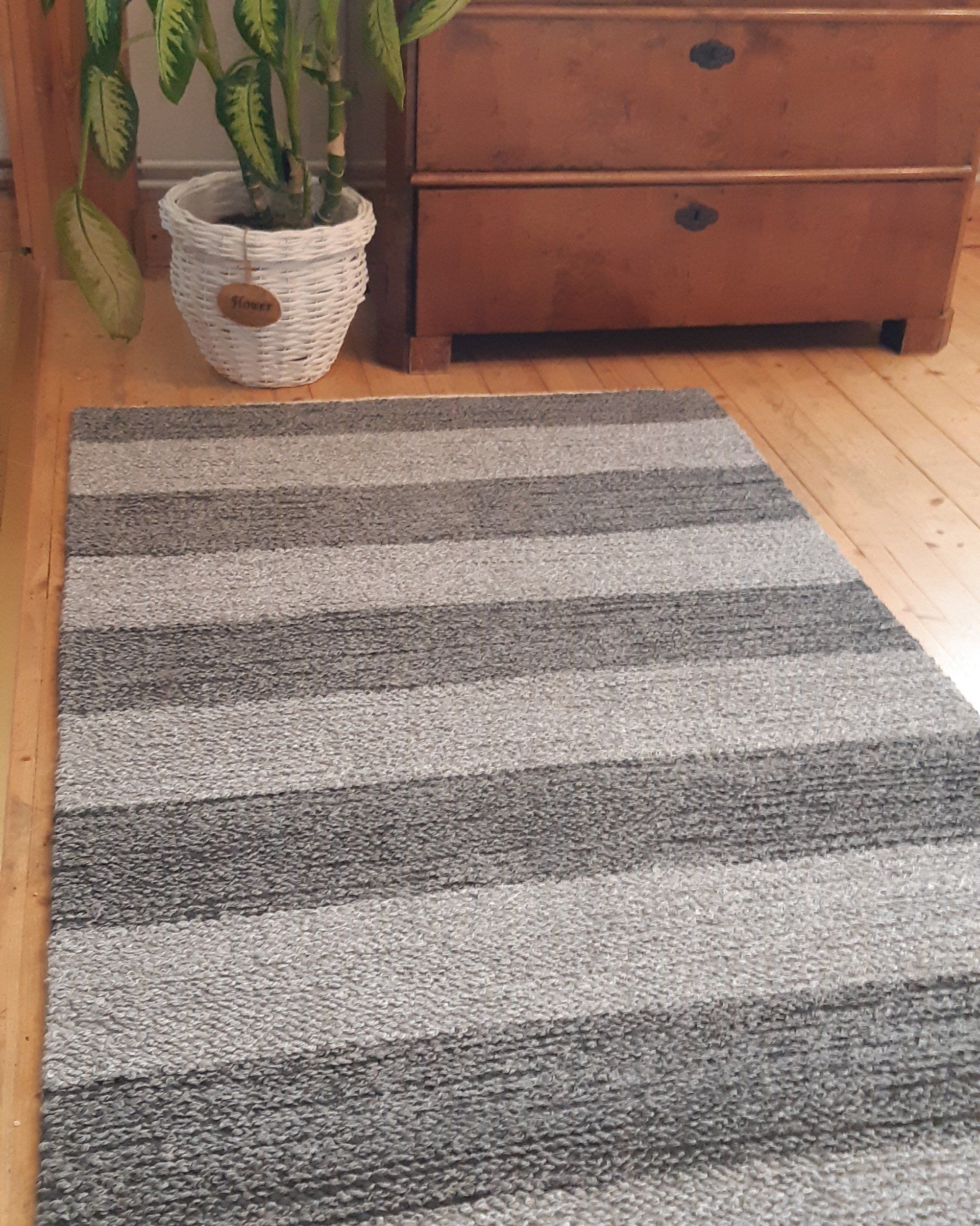 Raidallinen matto on puulattialla ruukkukasvin vieressä
