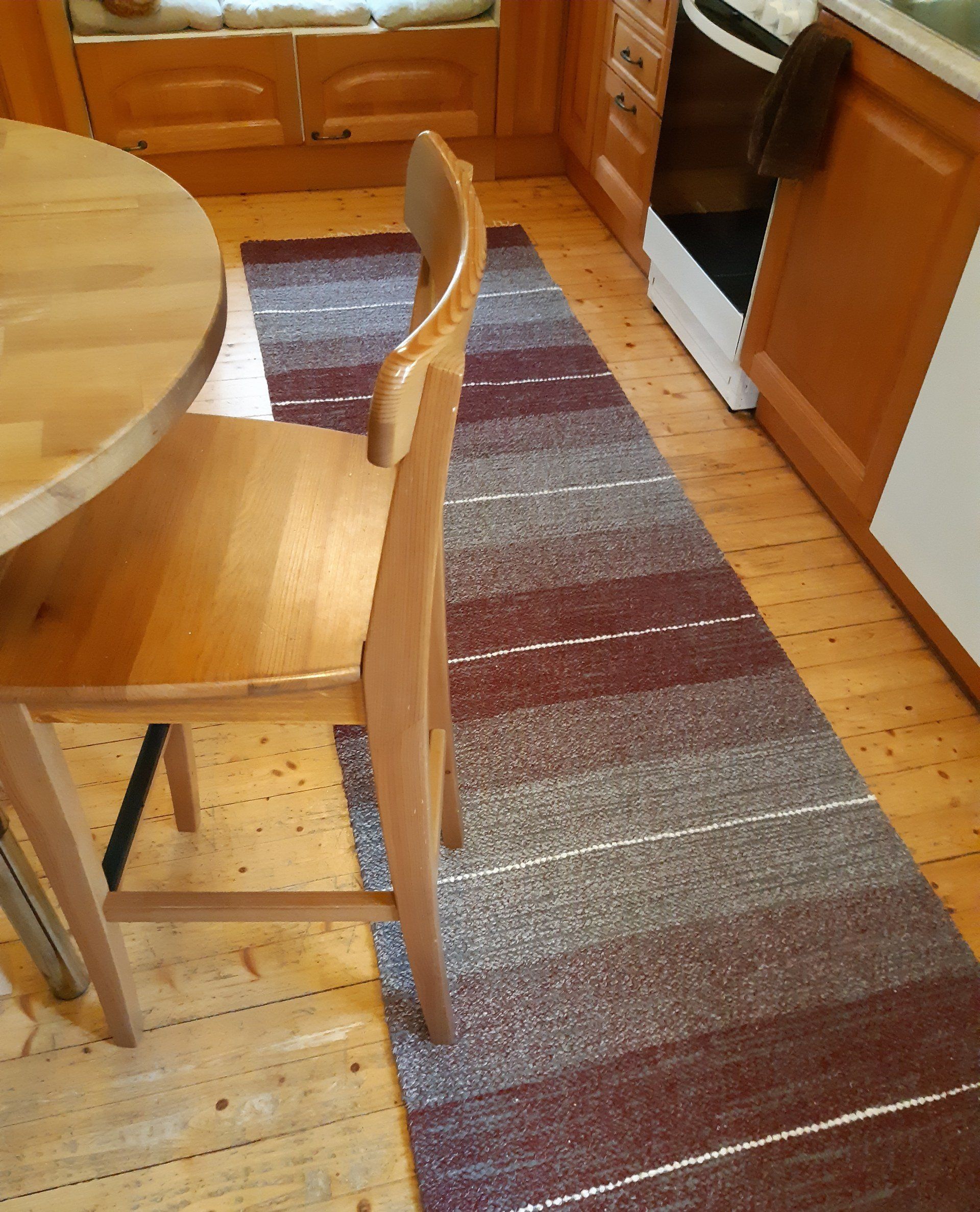 Keittiö, jossa on pöytä ja tuolit sekä matto lattialla