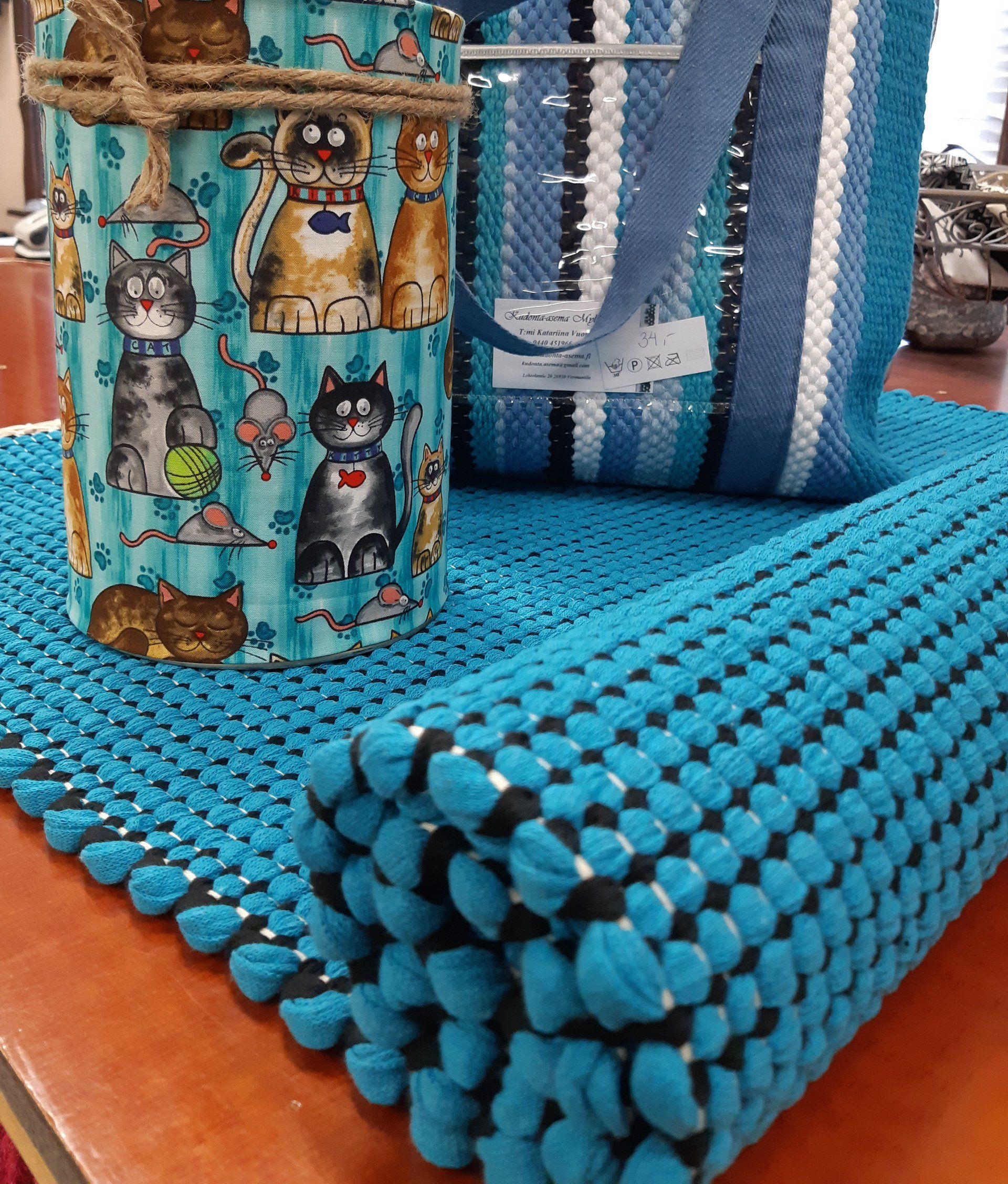 Pöytä, jolla on sininen matto ja sininen laukku, jossa on kissoja