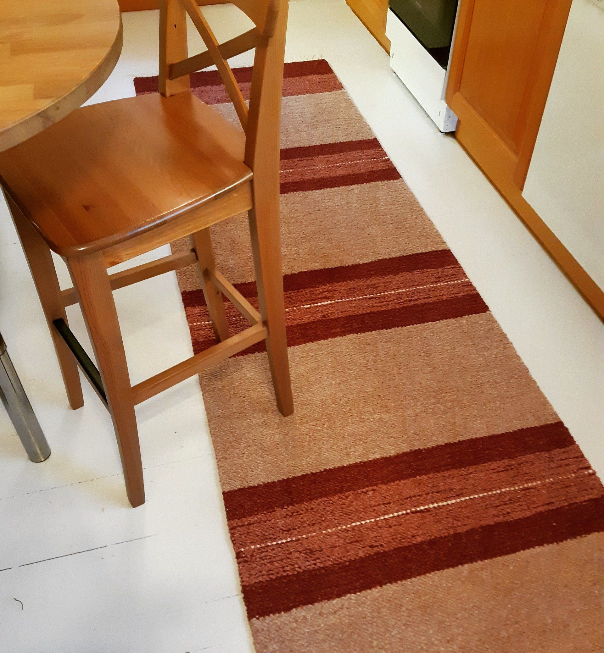 Puinen tuoli on raidallisen maton vieressä keittiössä