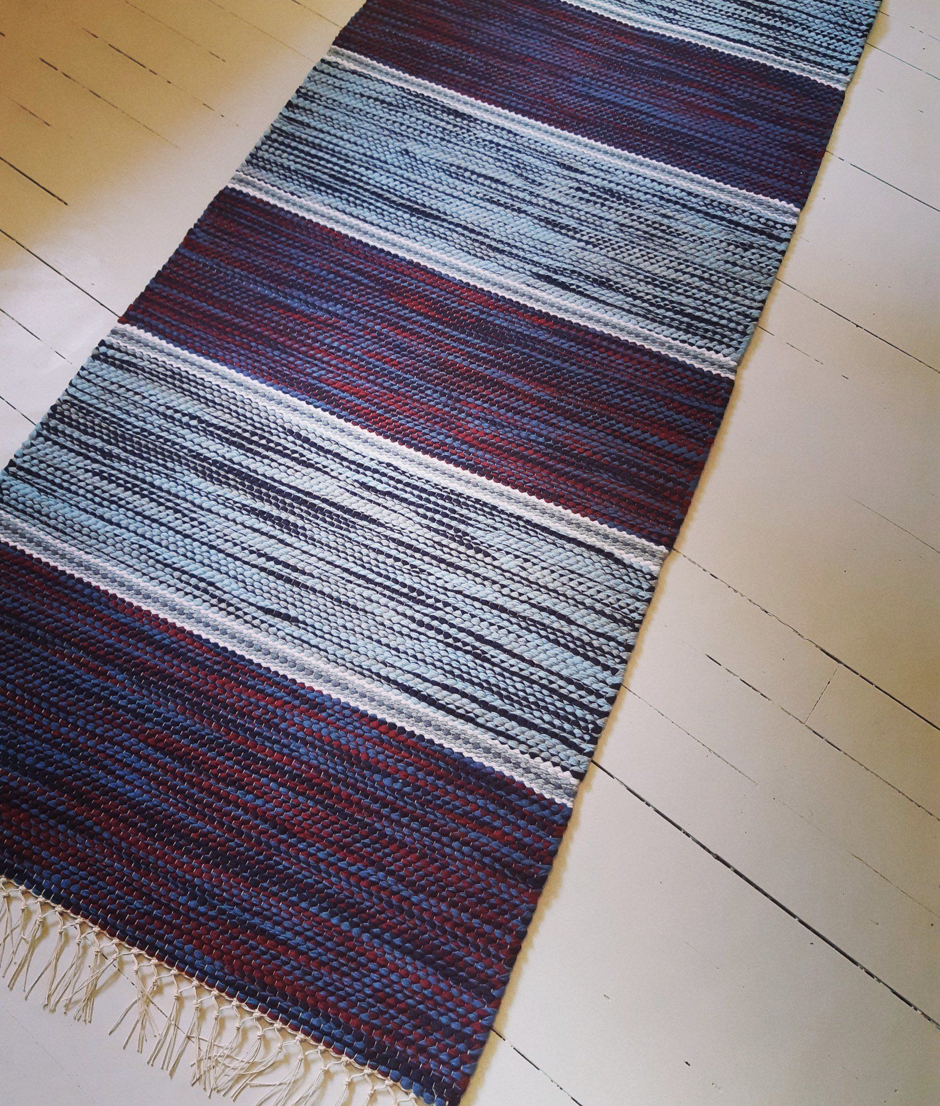 Sini-violettiraidallinen matto makaa valkoisella lattialla