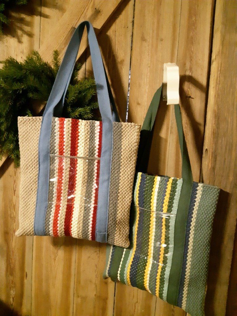 Kaksi raidallista laukkua roikkuu puisella seinällä