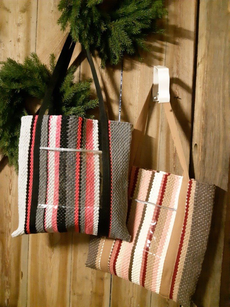 Kaksi raidallista laukkua roikkuu puisella seinällä