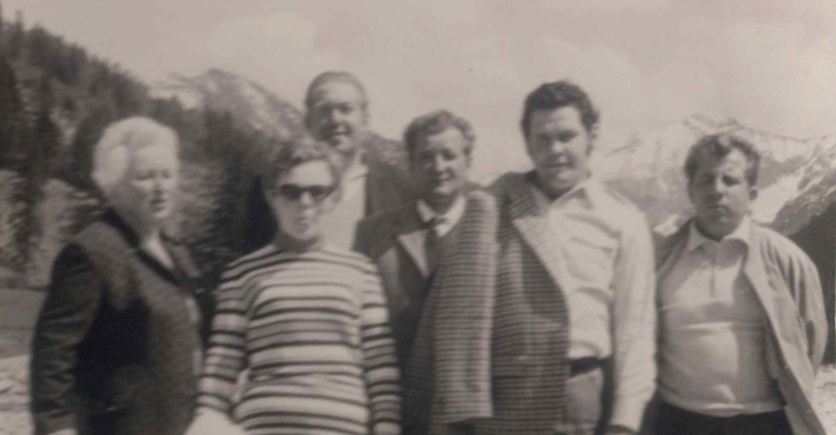 Schwarz-weißes Foto von sechs Personen, die eng nebeneinander im Freien stehen und in die Kamera schauen.