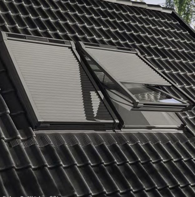 Dachfenster mit geschlossenem Außenrollo auf einem dunklen Ziegeldach.