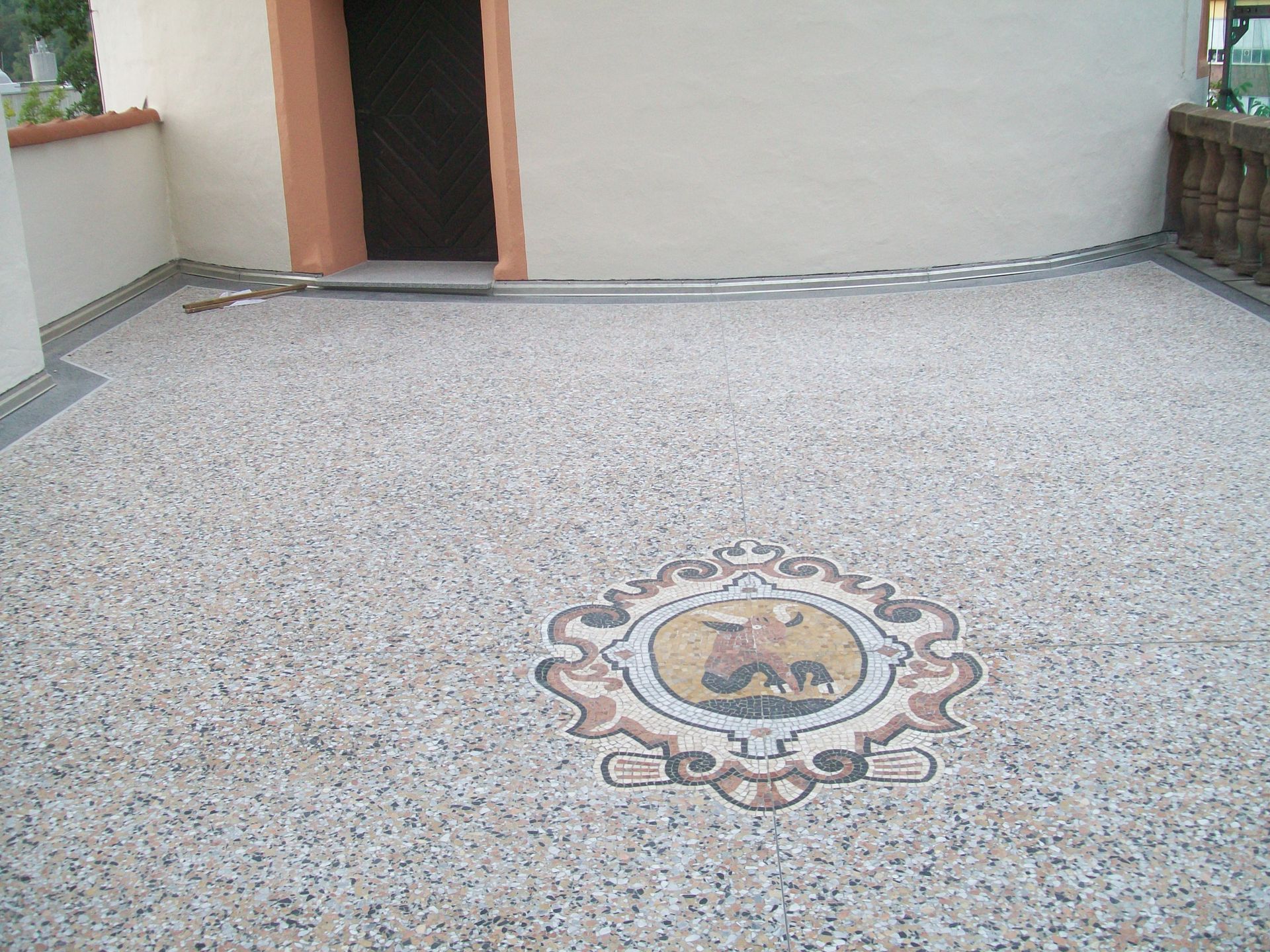 Balkonfläche mit Steinteppich und dekorativem Mosaikmuster.