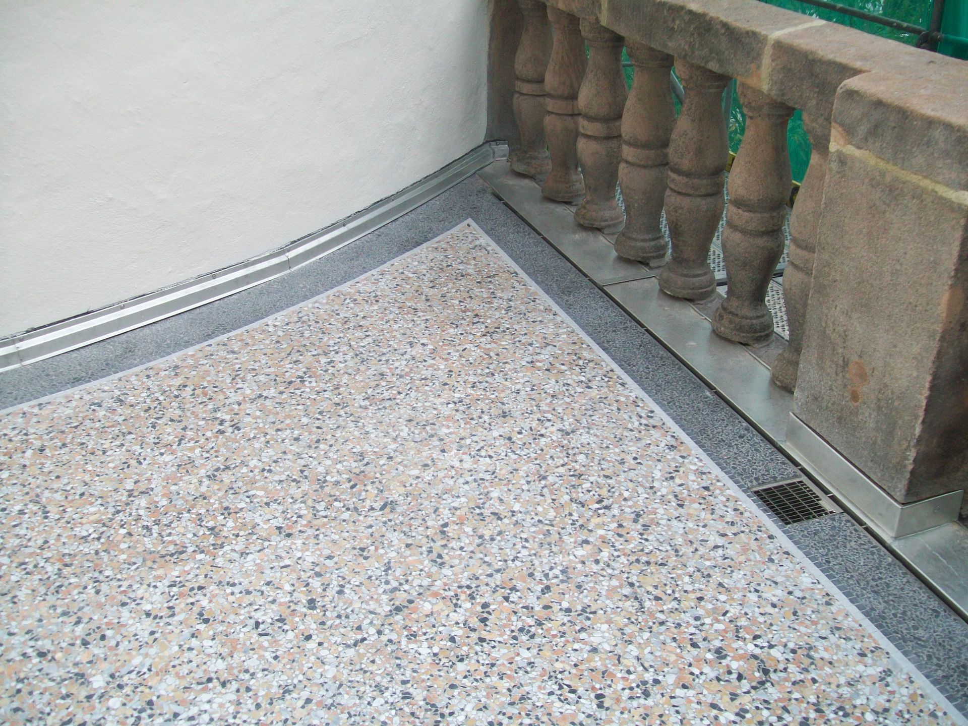 Detailaufnahme eines Balkons mit Steinteppich und Steinbrüstung.