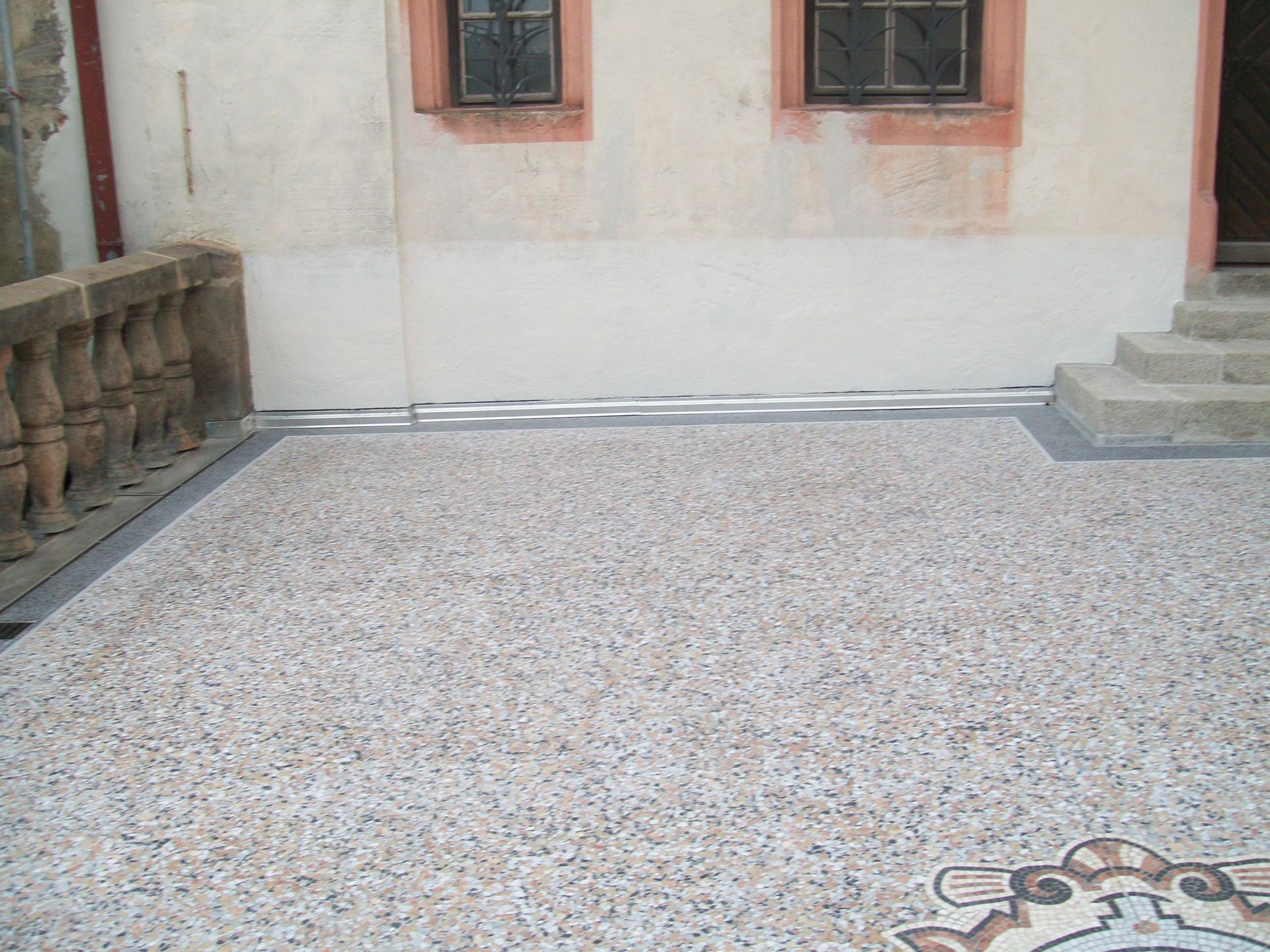 Balkonterrasse mit Steinteppich und Treppenaufgang zum Hauseingang.