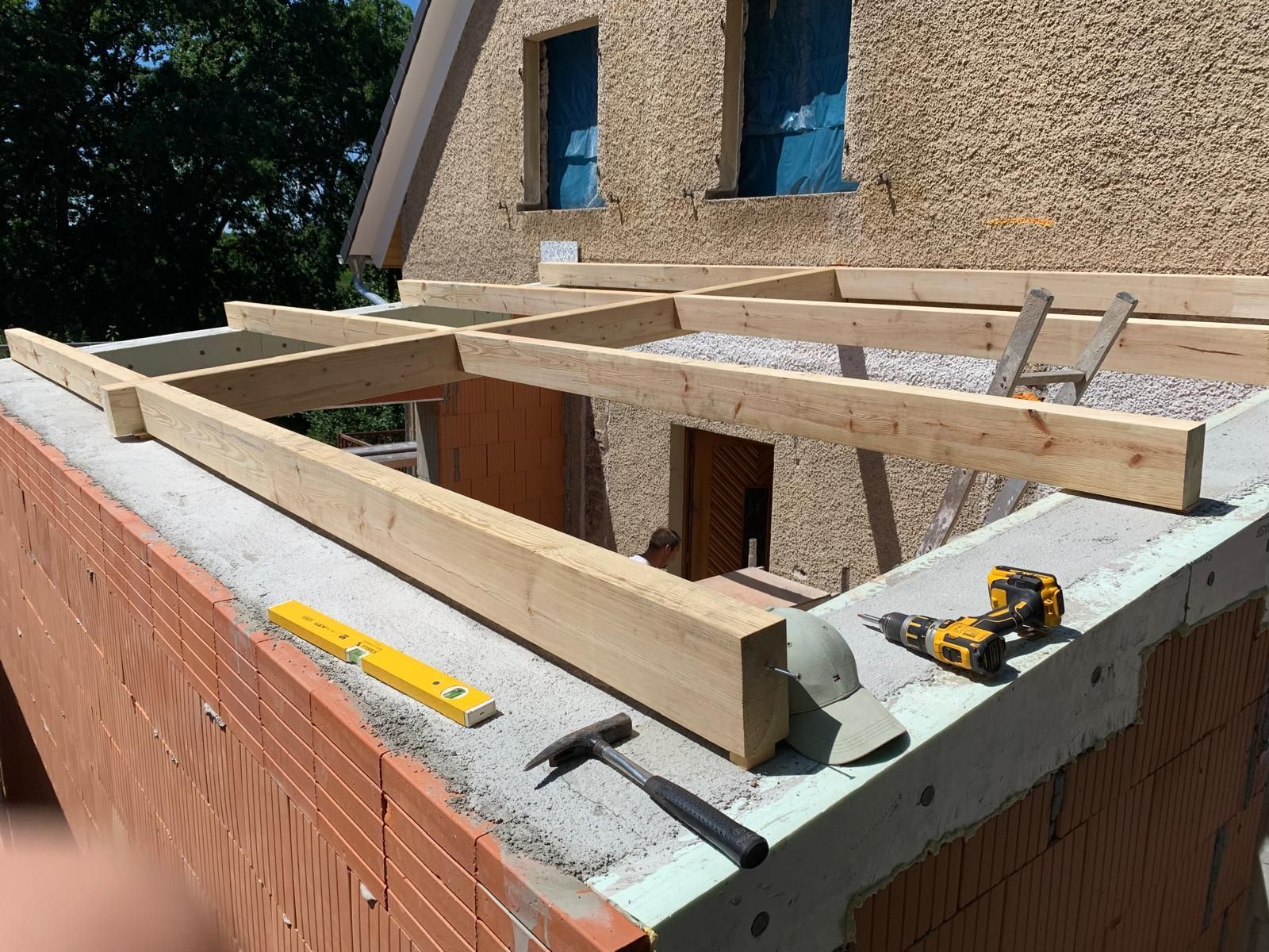 Holzbalken für einen Carport-Anbau werden auf einer Hauswand montiert