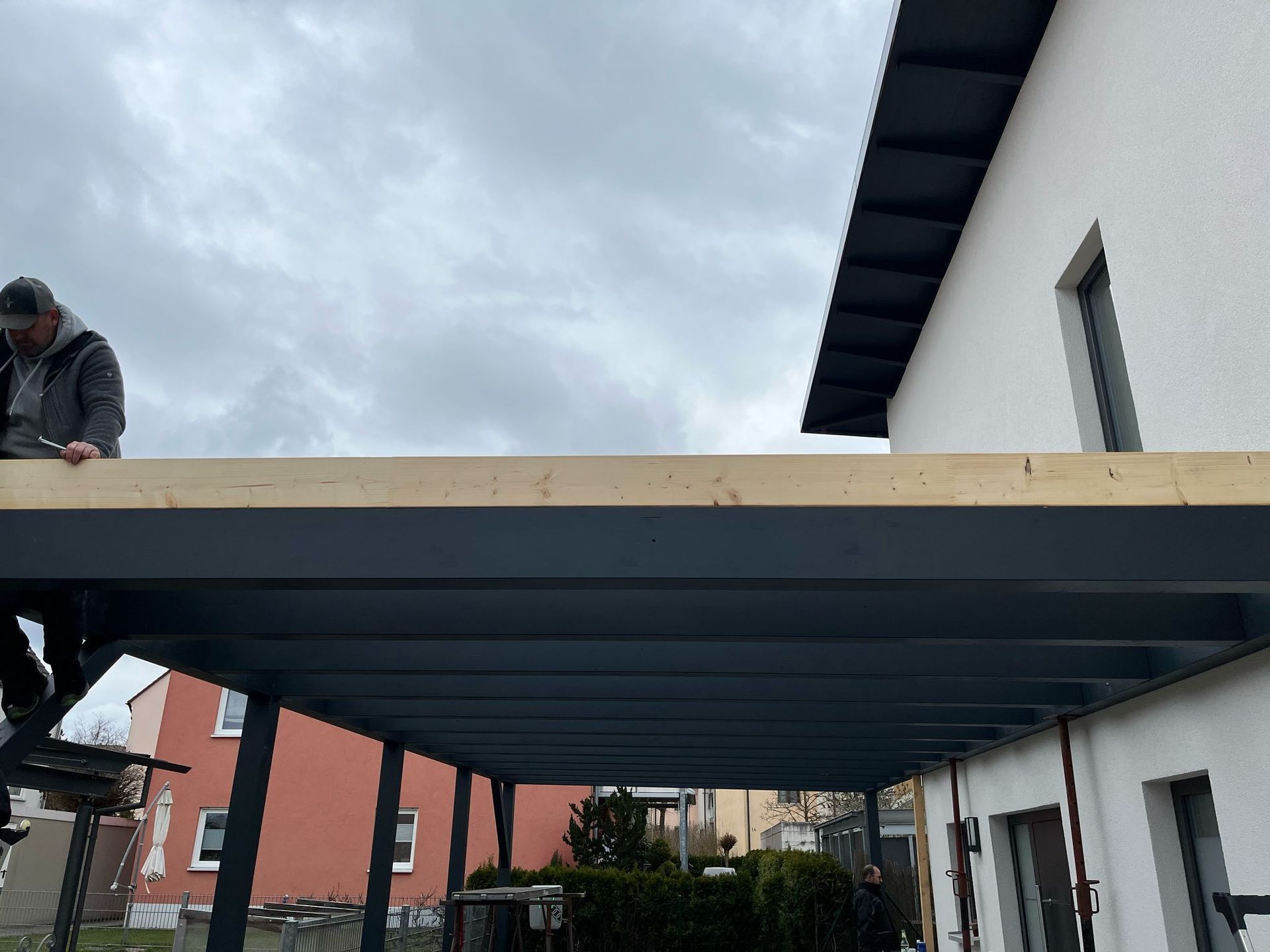 Montage der Dachkonstruktion eines modernen Carports mit Holzbalken und Stahlträgern