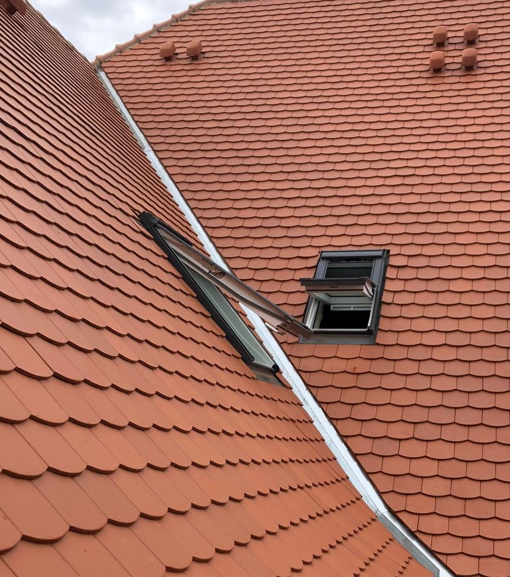 Mehrere Dachfenster auf einem neu gedeckten roten Ziegeldach.