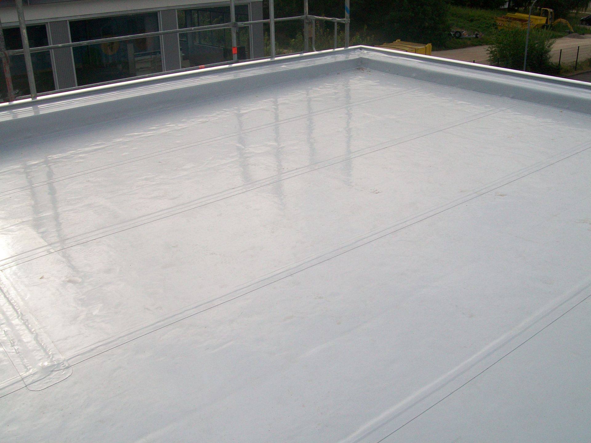 Modernes Flachdach mit reflektierender Dachfolie und Attika.