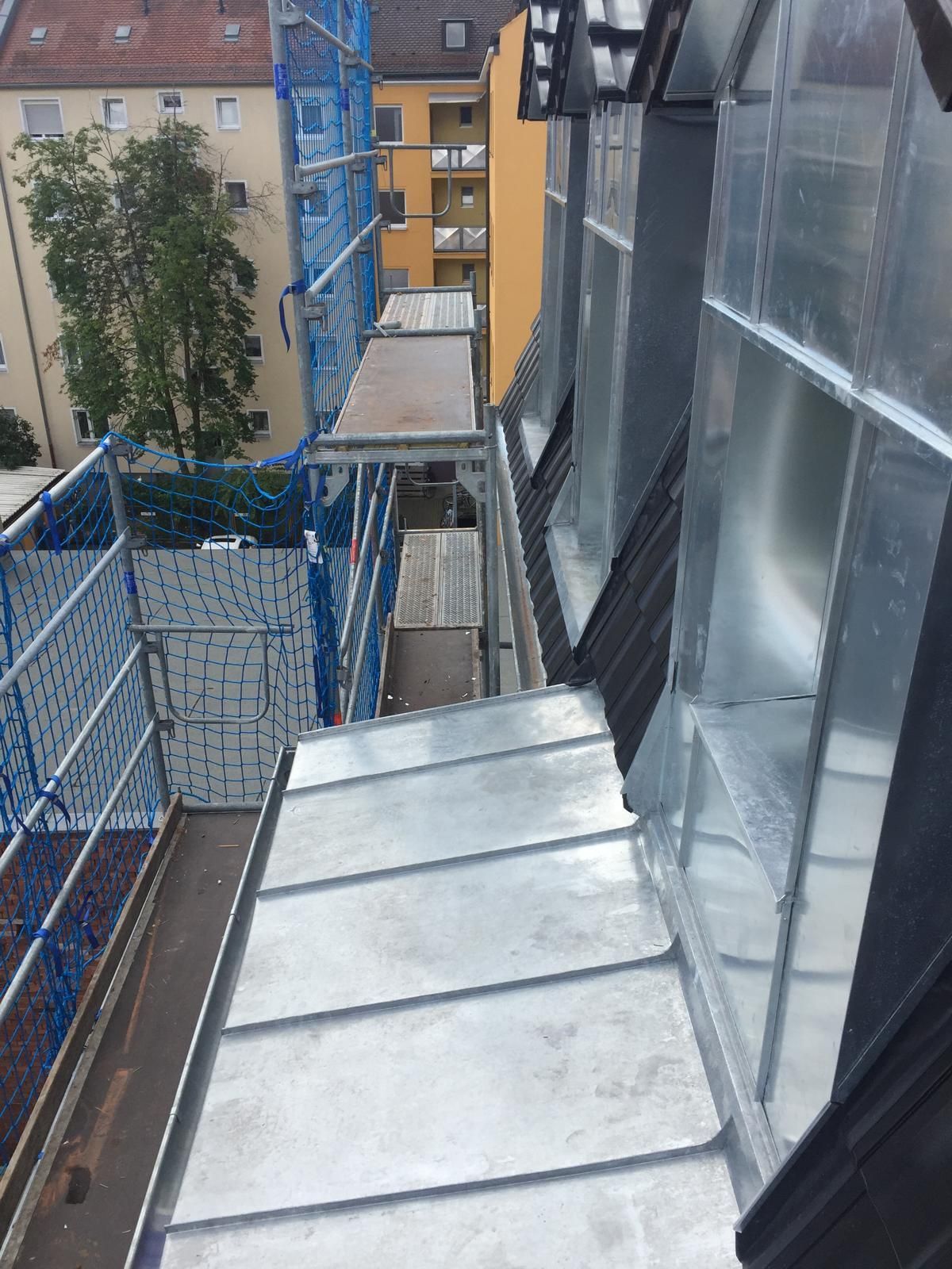 Metallverkleidete Dachfassade mit Gerüst an einem Mehrfamilienhaus in urbaner Umgebung