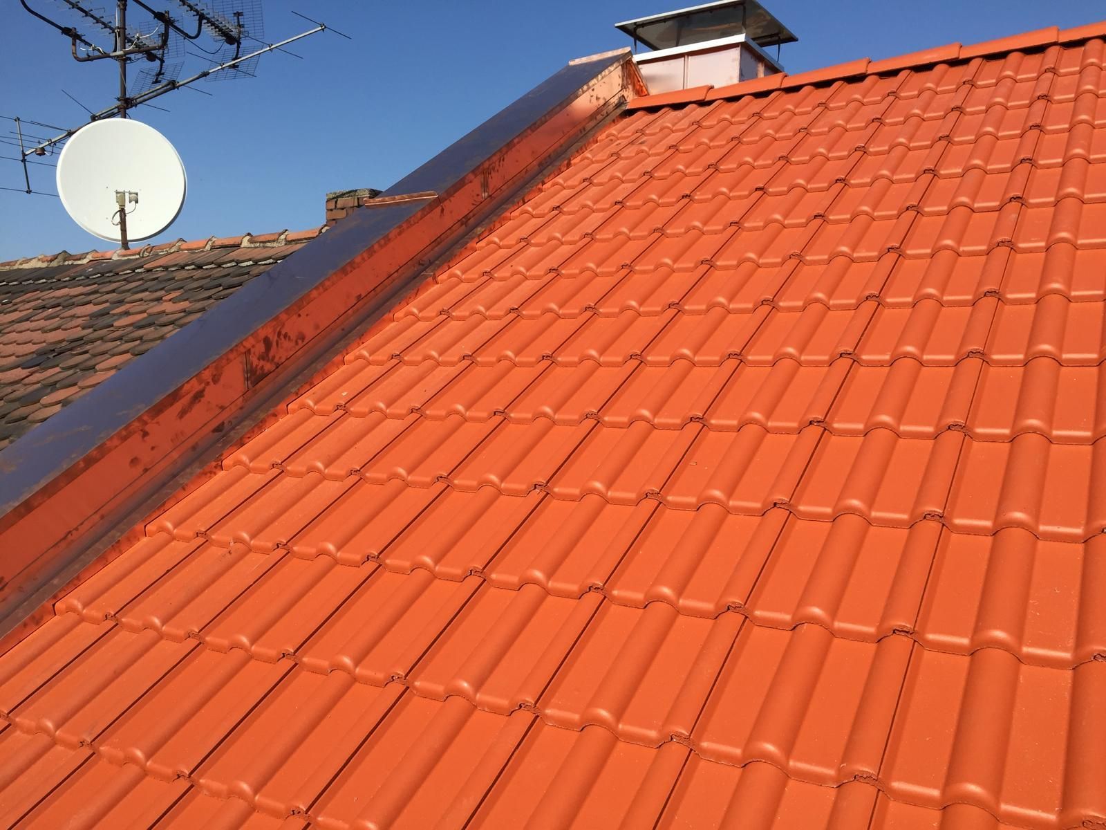 Neu eingedecktes Satteldach mit roten Dachziegeln und sauber verarbeitetem Dachanschluss bei sonnigem Wetter