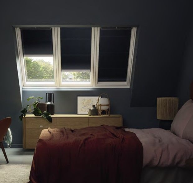 Dachfenster mit verdunkelnden Innenrollos in modern eingerichtetem Schlafzimmer.