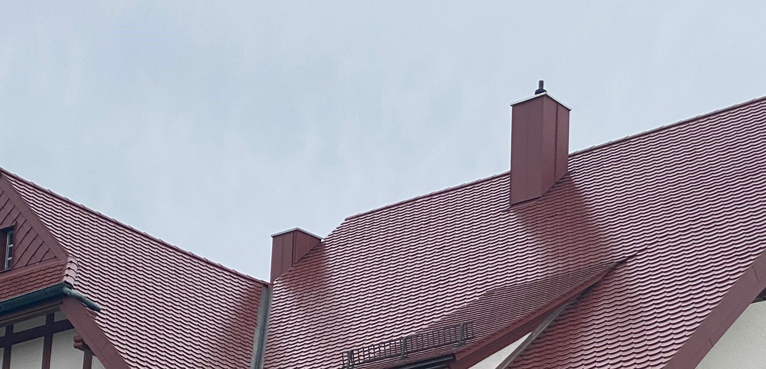 Rotes Ziegeldach mit mehreren Schornsteinen und Dachanschlüssen
