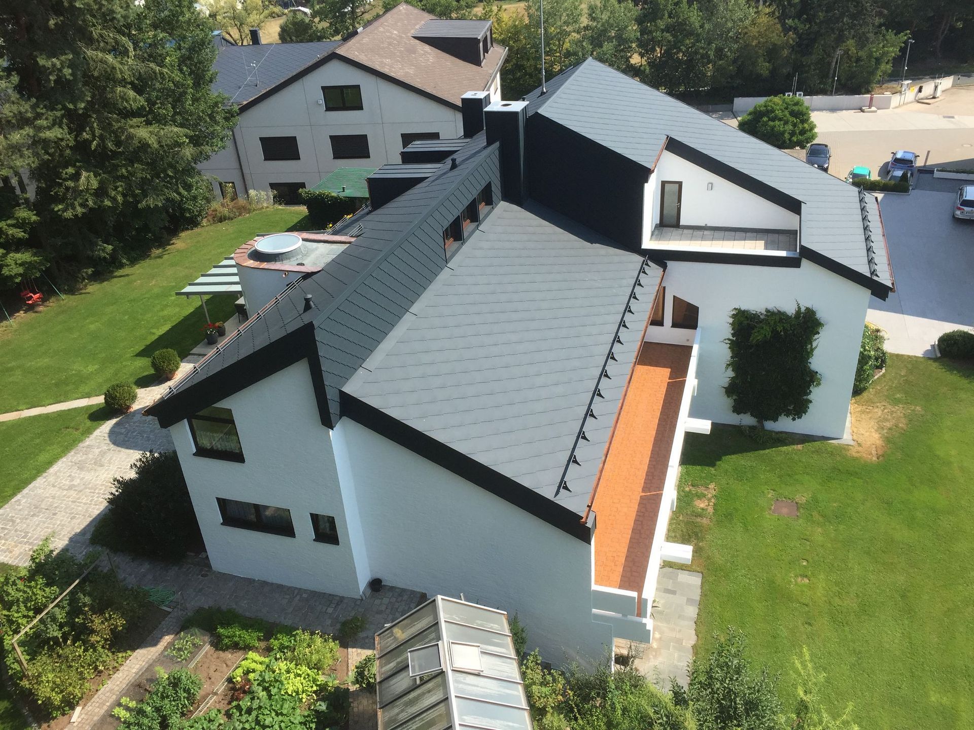 Wohnhaus mit dunklem Steildach aus Metallschindeln aus der Luft aufgenommen