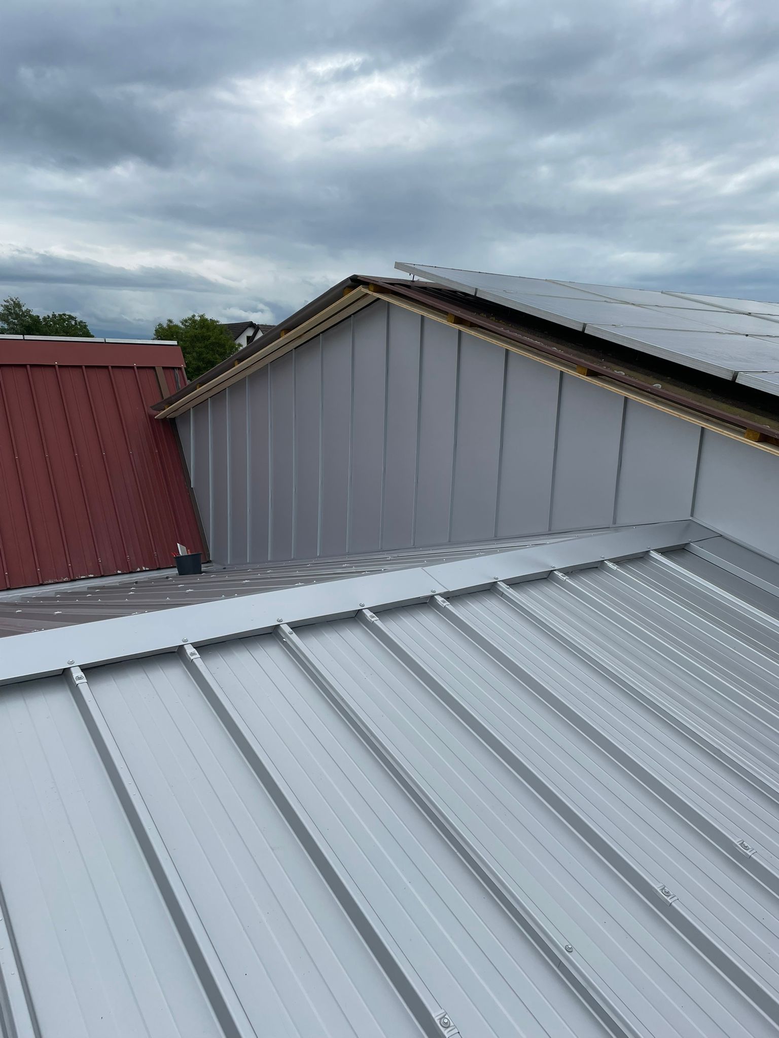 Modernes Steildach mit schwarzer Metalldeckung und integrierter Solaranlage unter bewölktem Himmel