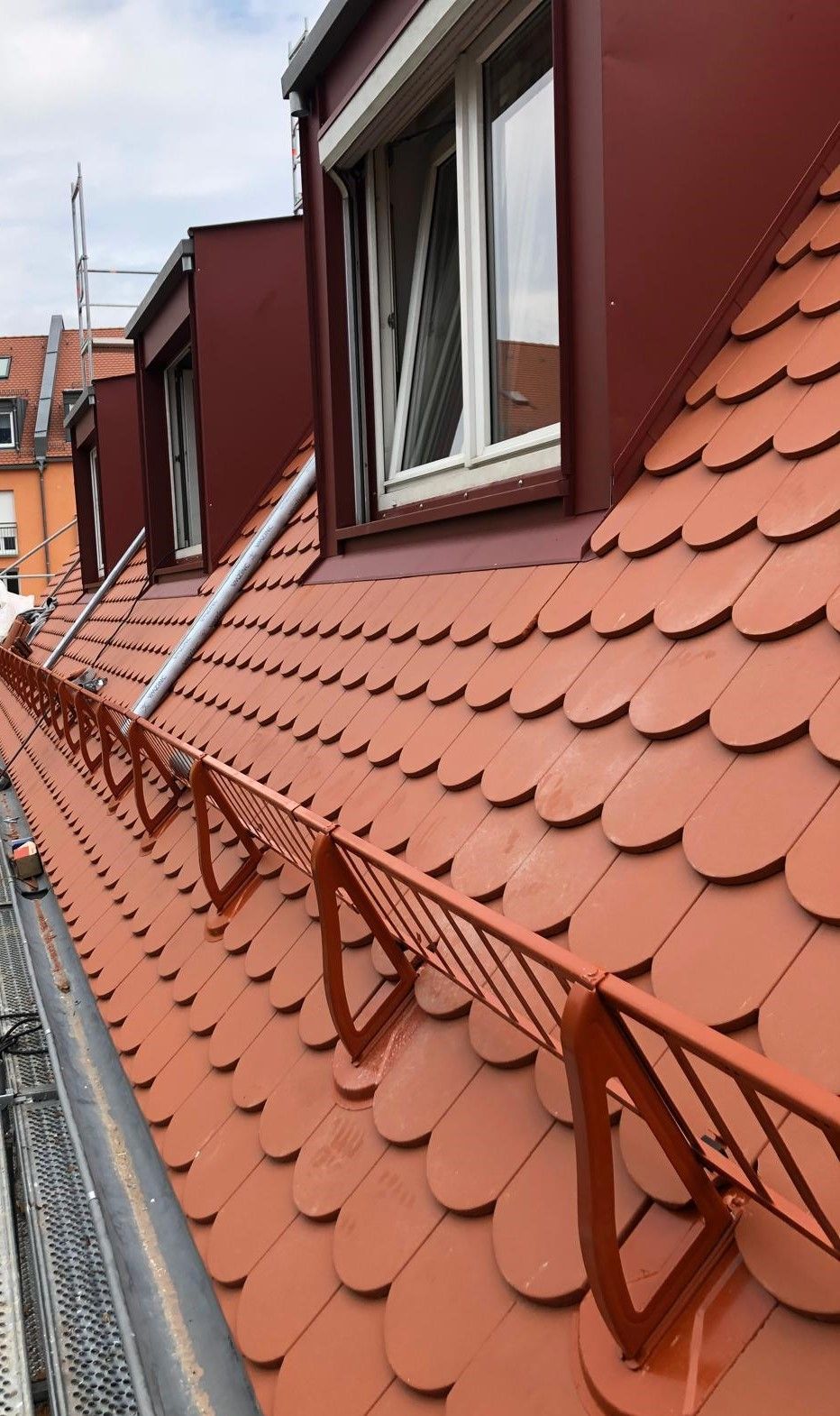 Dachgaube mit roter Fassadenverkleidung und Ziegeldach an einem Wohnhaus.