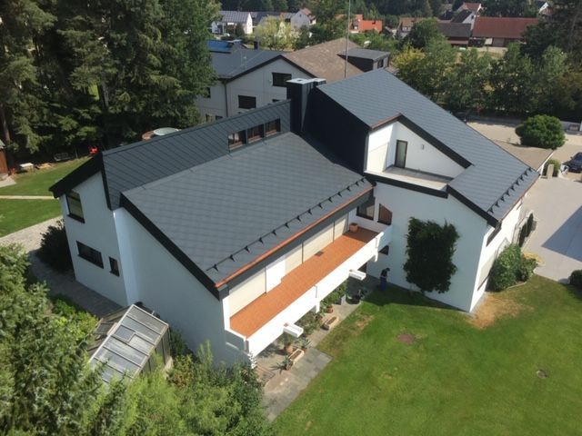 Großes Einfamilienhaus mit grauem Schindeldach aus der Luftperspektive