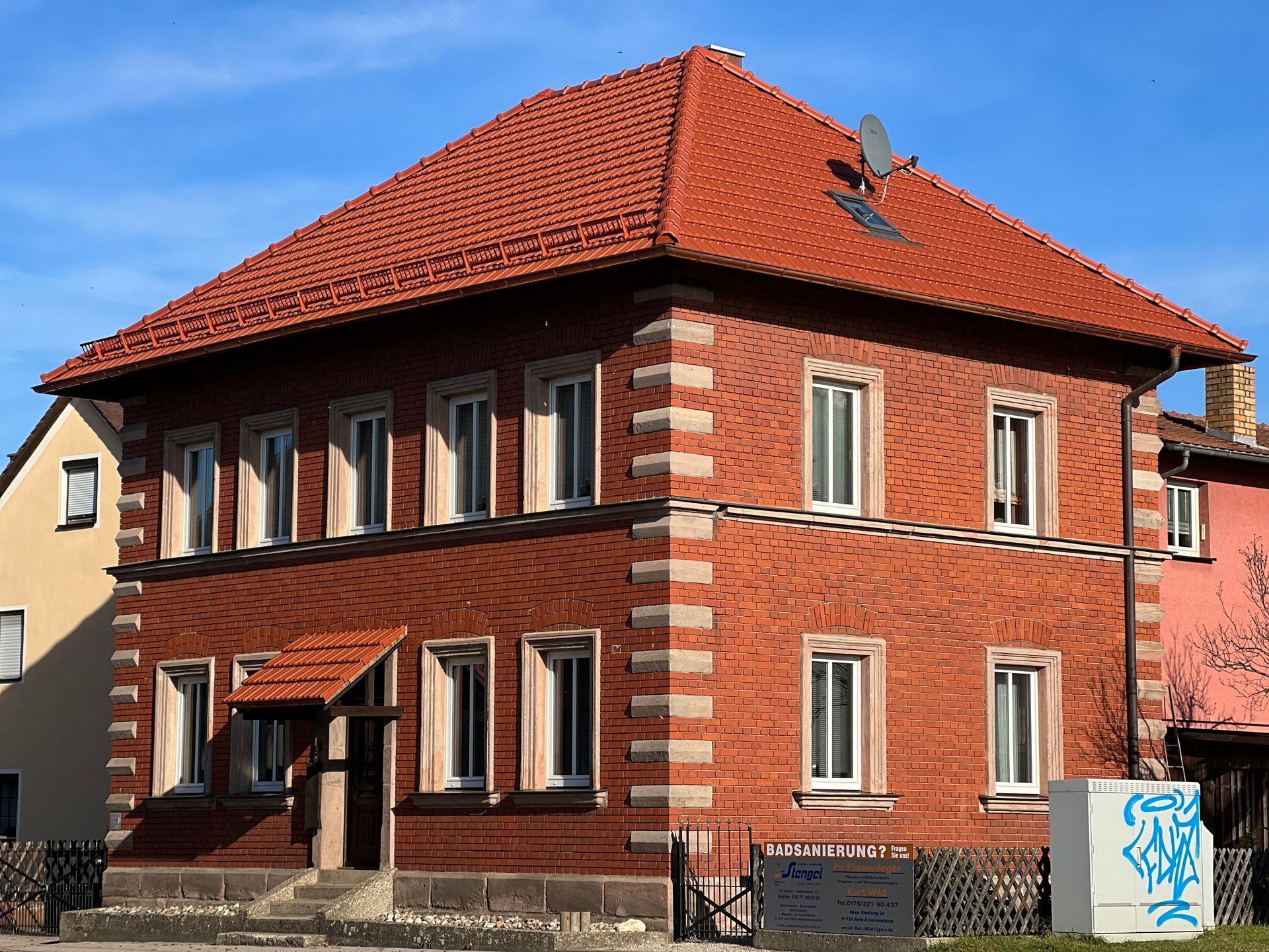 Historisches Backsteingebäude mit rotem Steildach und symmetrischer Fensterfront
