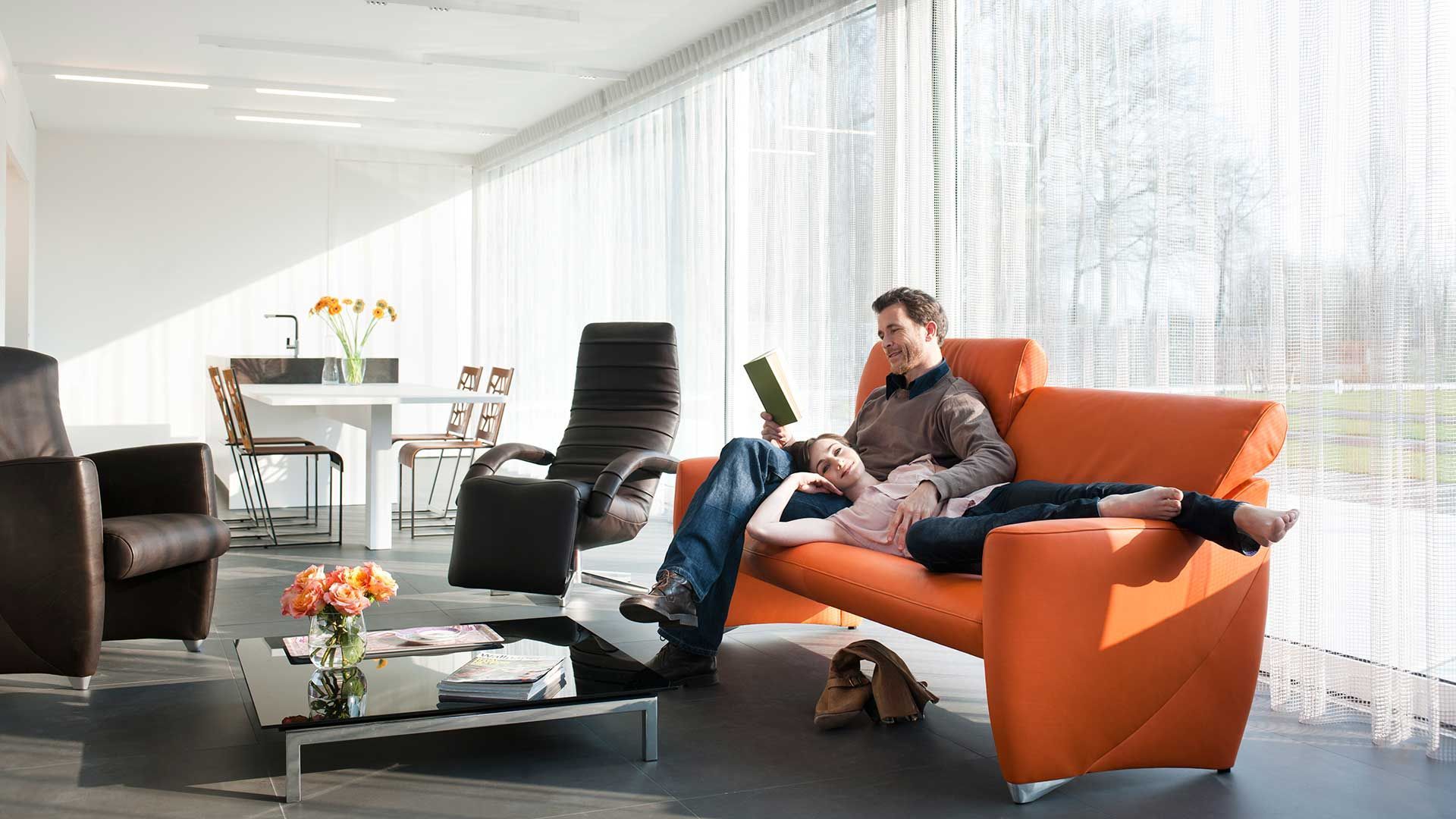 Pärchen liegt auf einem orangenen Sofa  von JORI