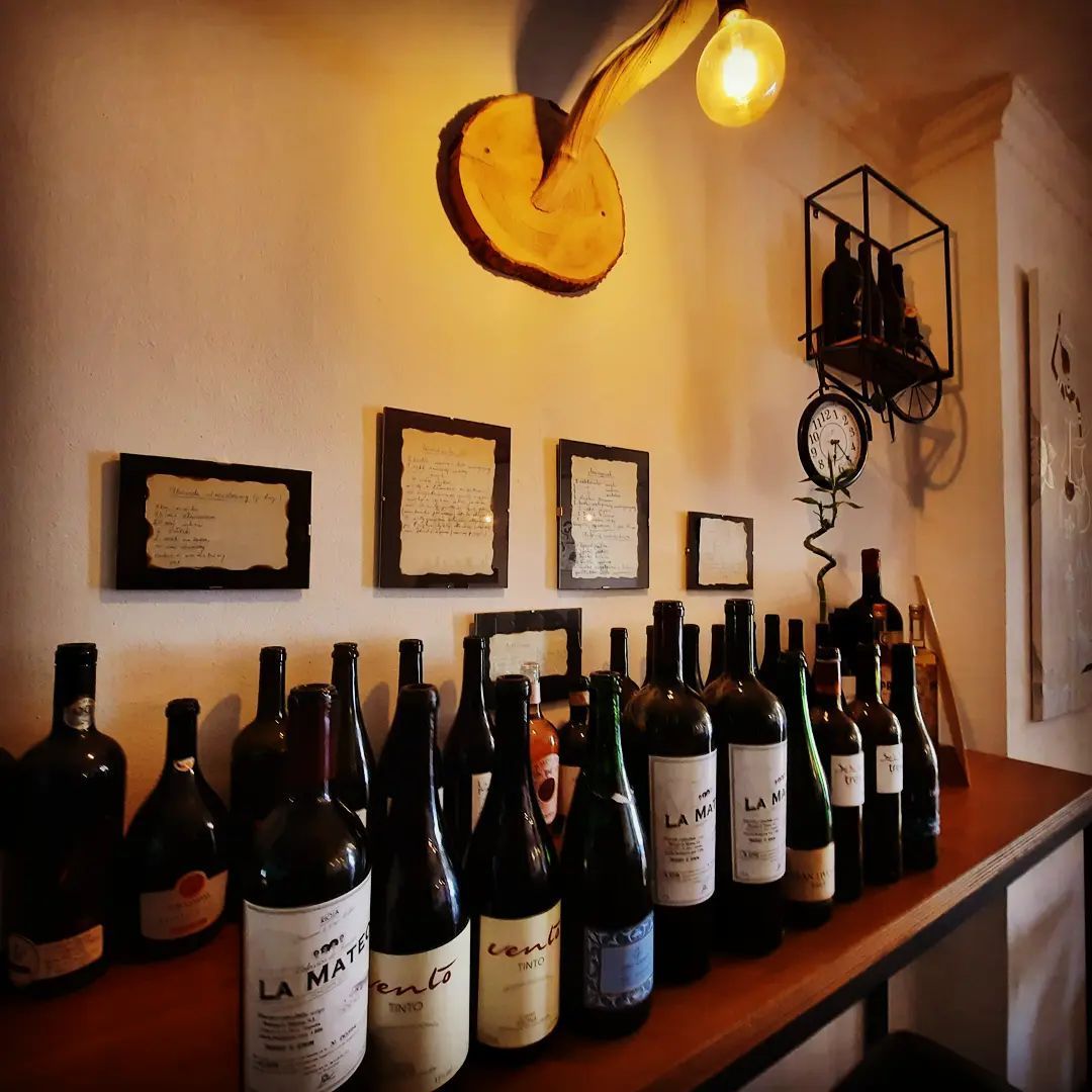 Una fila de botellas de vino están alineadas en un estante