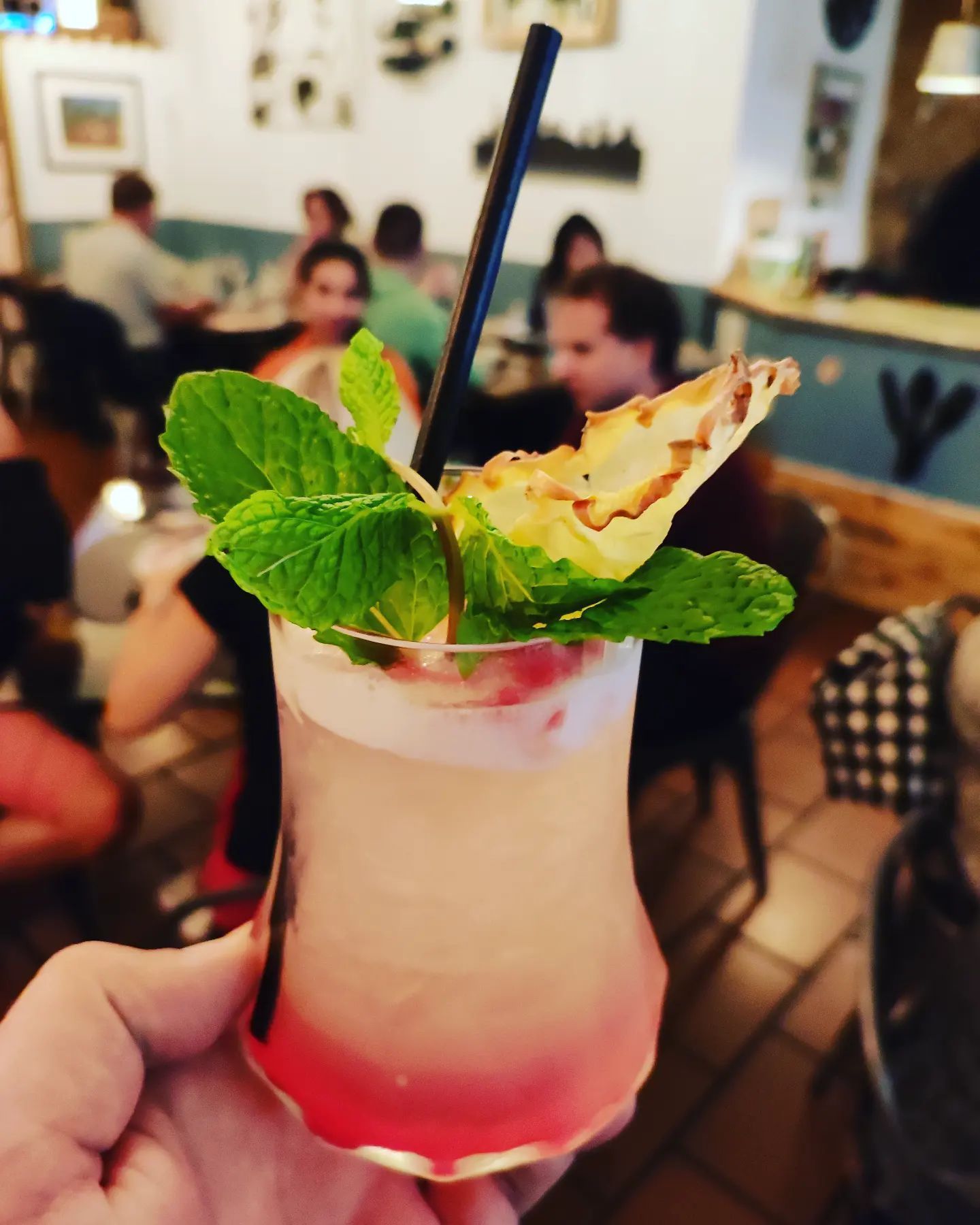 Una persona sostiene una bebida con una rodaja de piña encima.