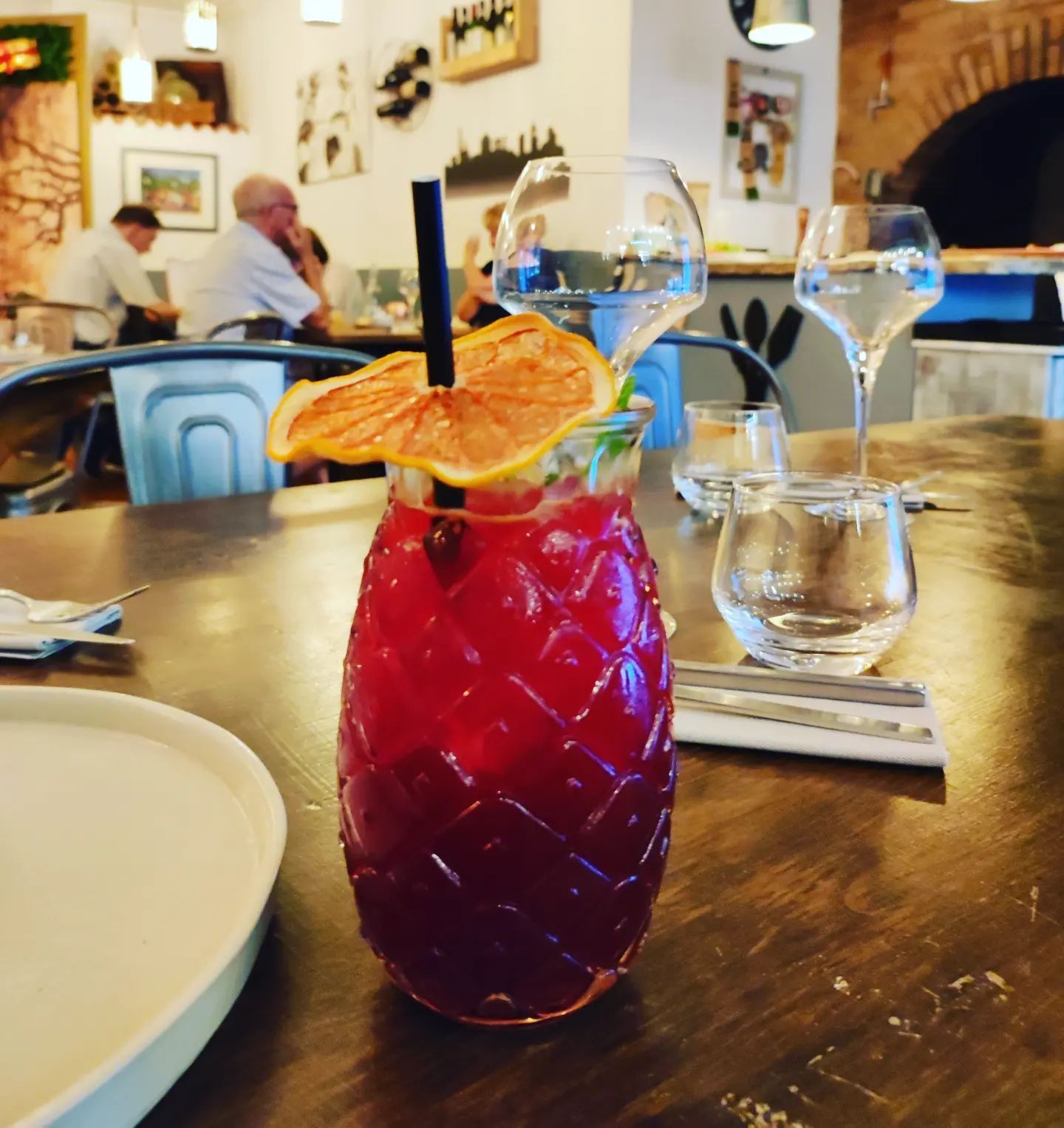 Una bebida roja en un vaso con forma de piña y una pajita.