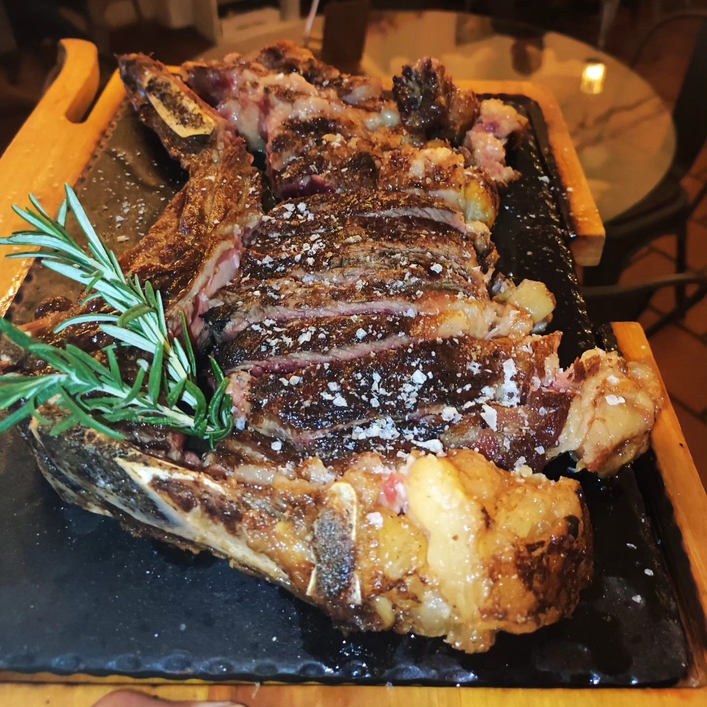 Un gran trozo de carne está sobre una bandeja de madera.