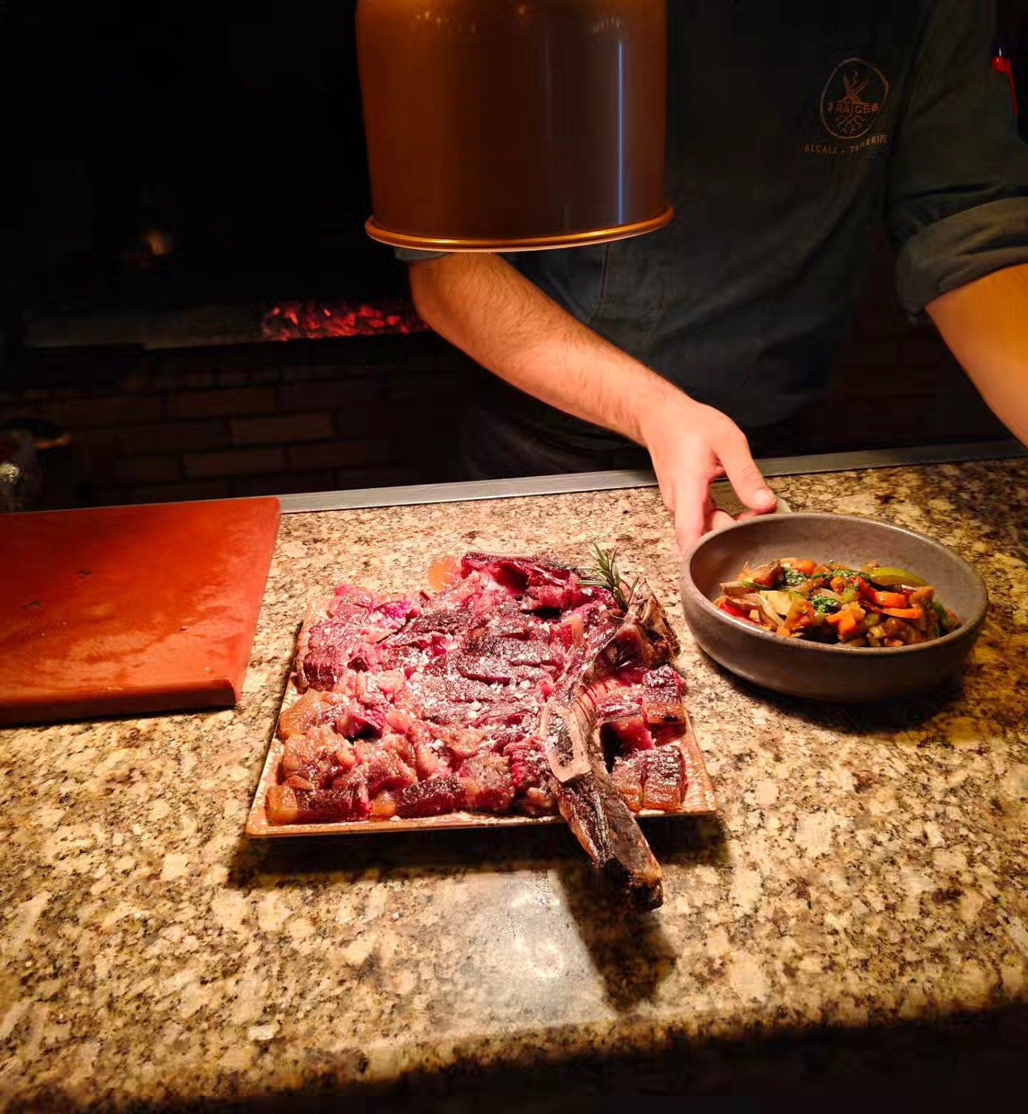 Un plato de carne y un tazón de verduras en un mostrador.