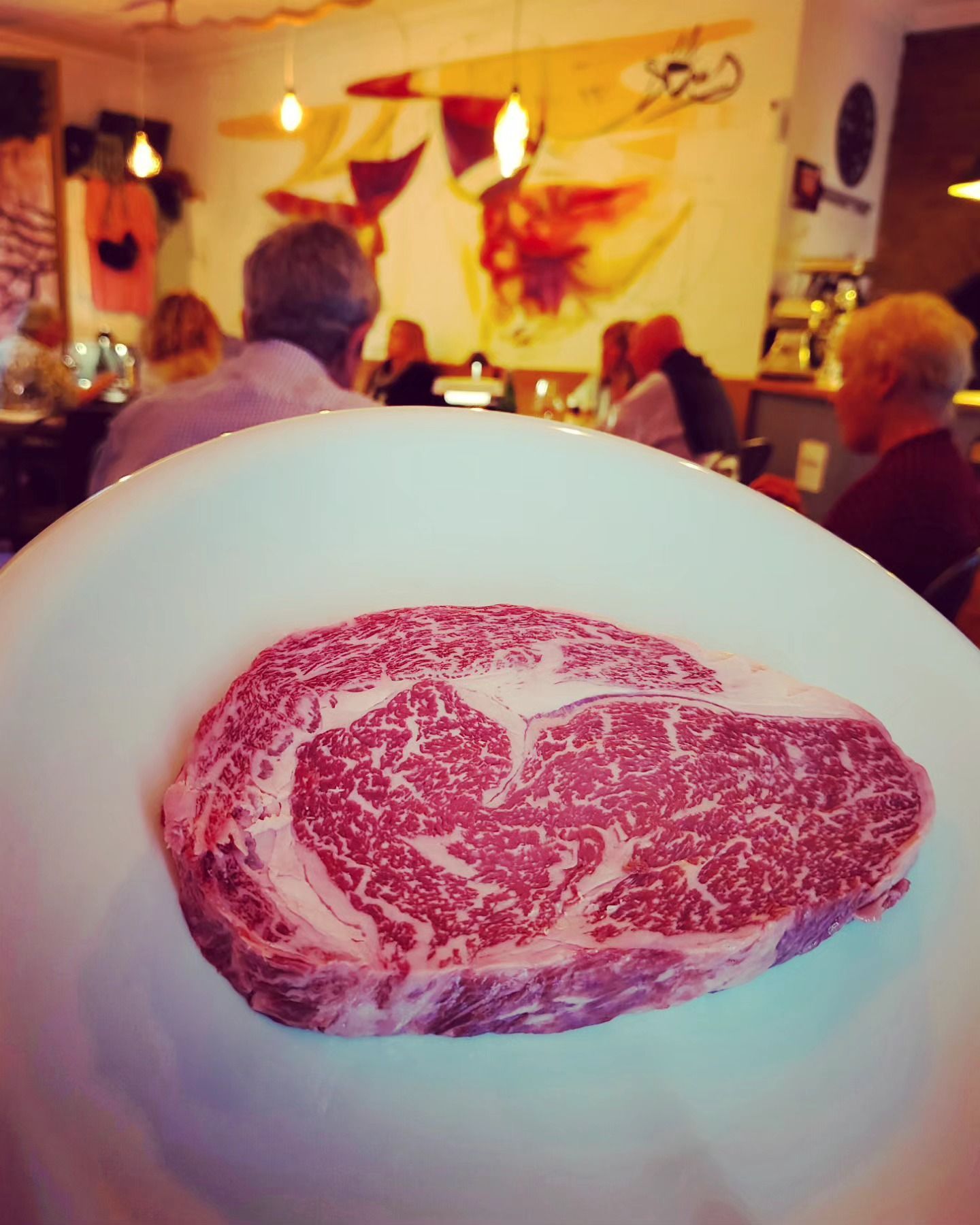 Un gran trozo de carne está en un plato blanco.