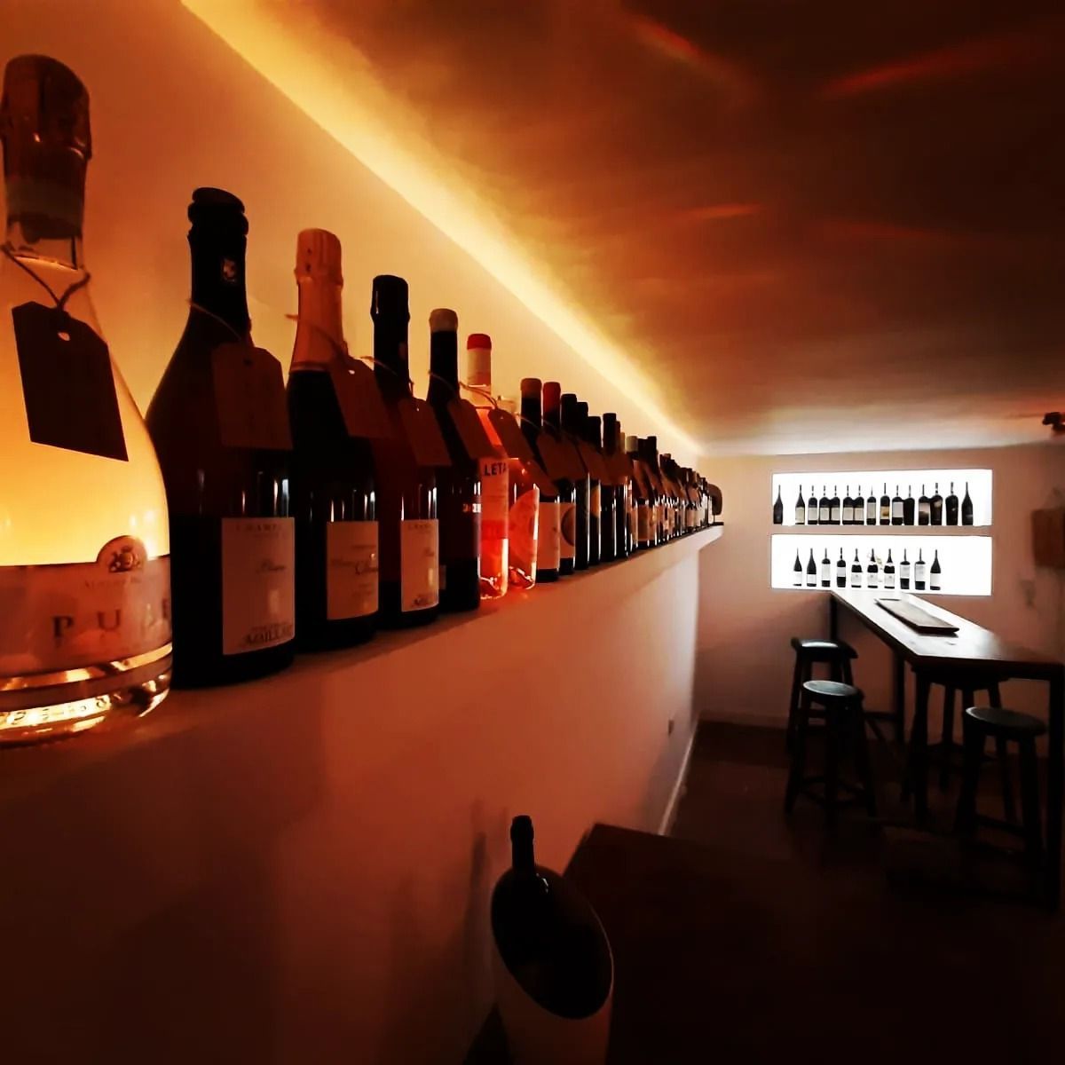 Una fila de botellas de vino están alineadas en un estante