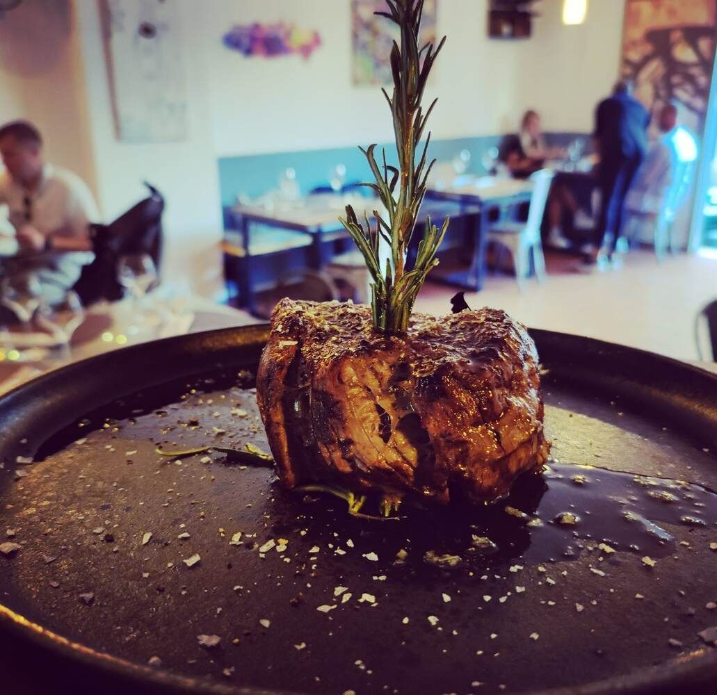 Un trozo de carne con una ramita de romero encima.