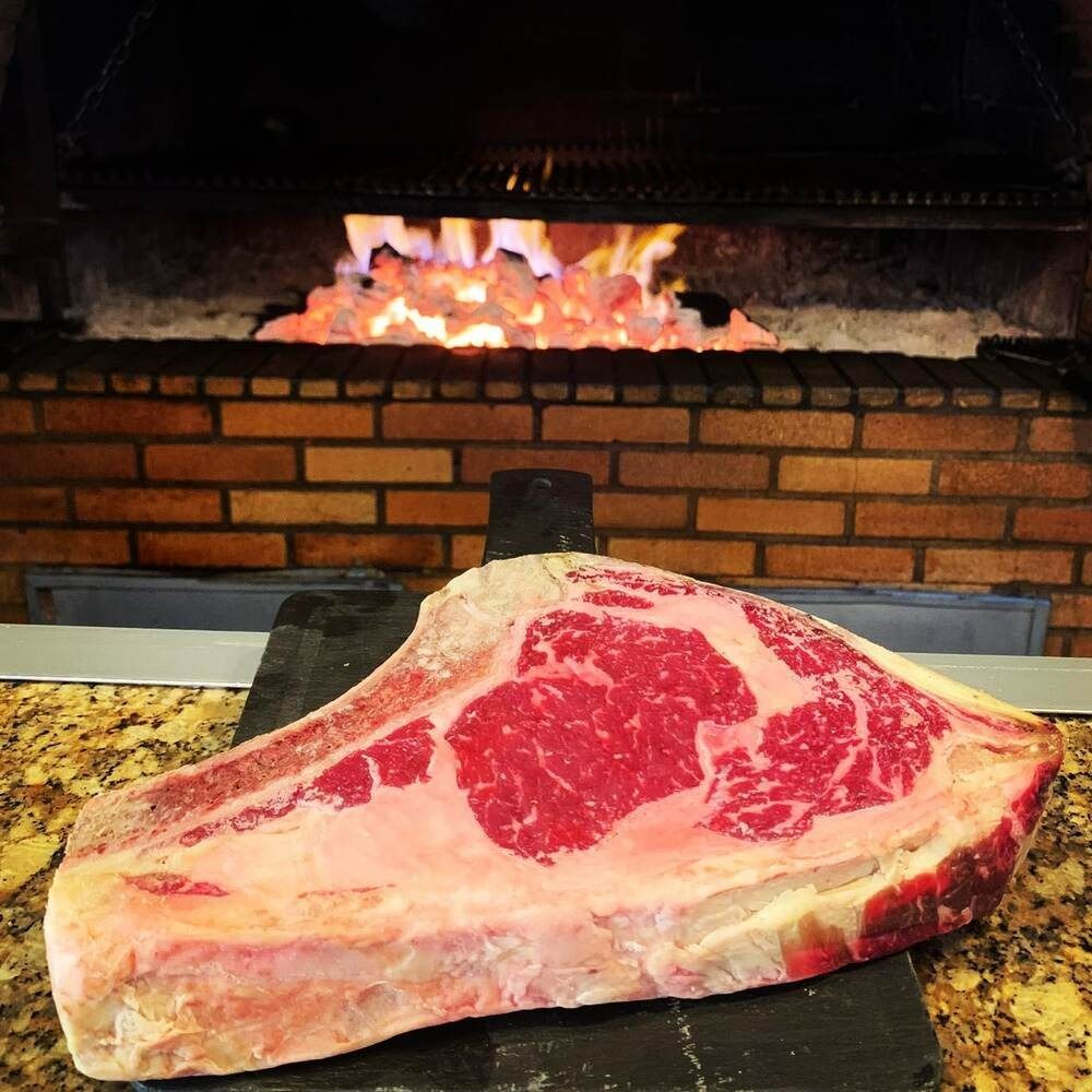 Un gran trozo de carne reposa sobre un mostrador frente a una chimenea.