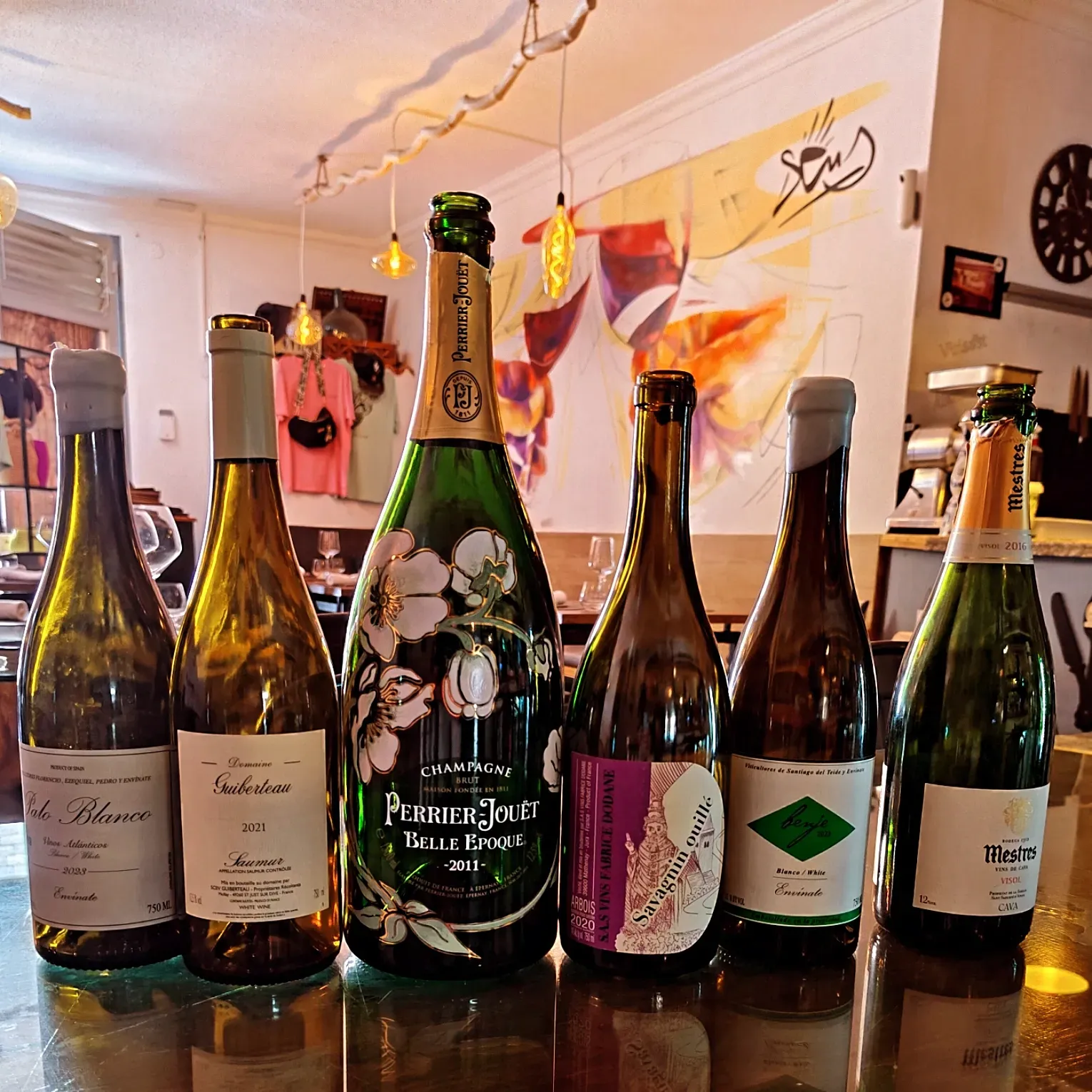 Varias botellas de vino están alineadas en un mostrador, incluida una botella que dice