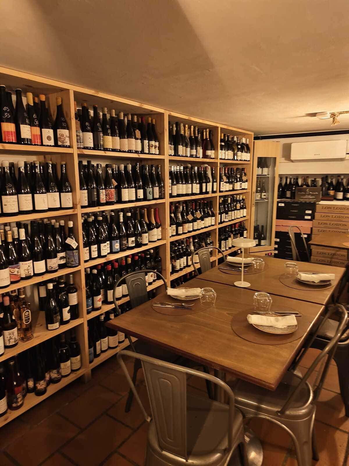 Comedor-bodega con estantes para botellas y una mesa de madera puesta para dos personas.