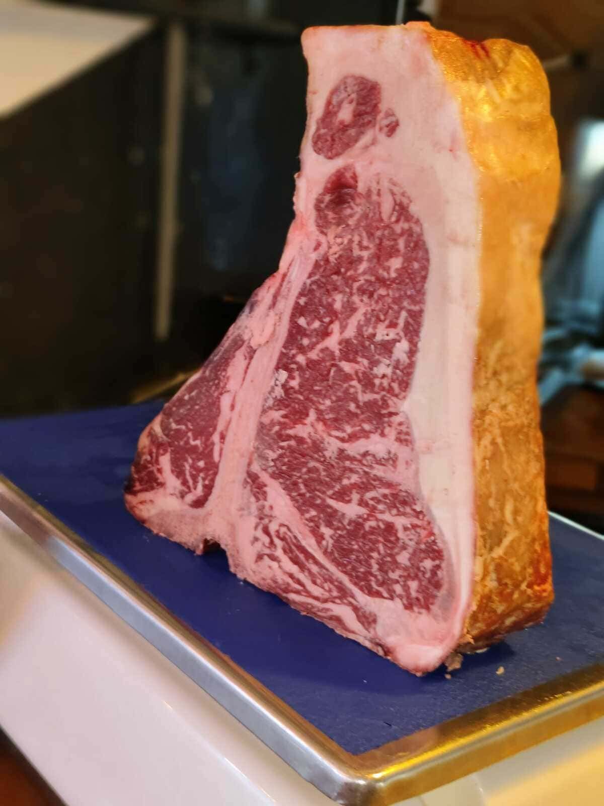 Filete veteado sobre un soporte de exhibición, con una capa de grasa de color marrón dorado y una base azul.