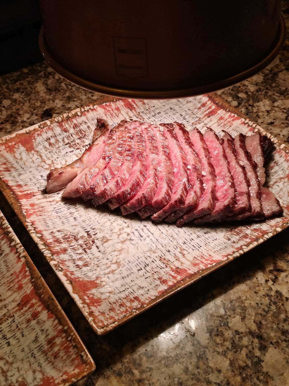 Filete poco hecho en rodajas sobre un plato estampado en la encimera de la cocina.