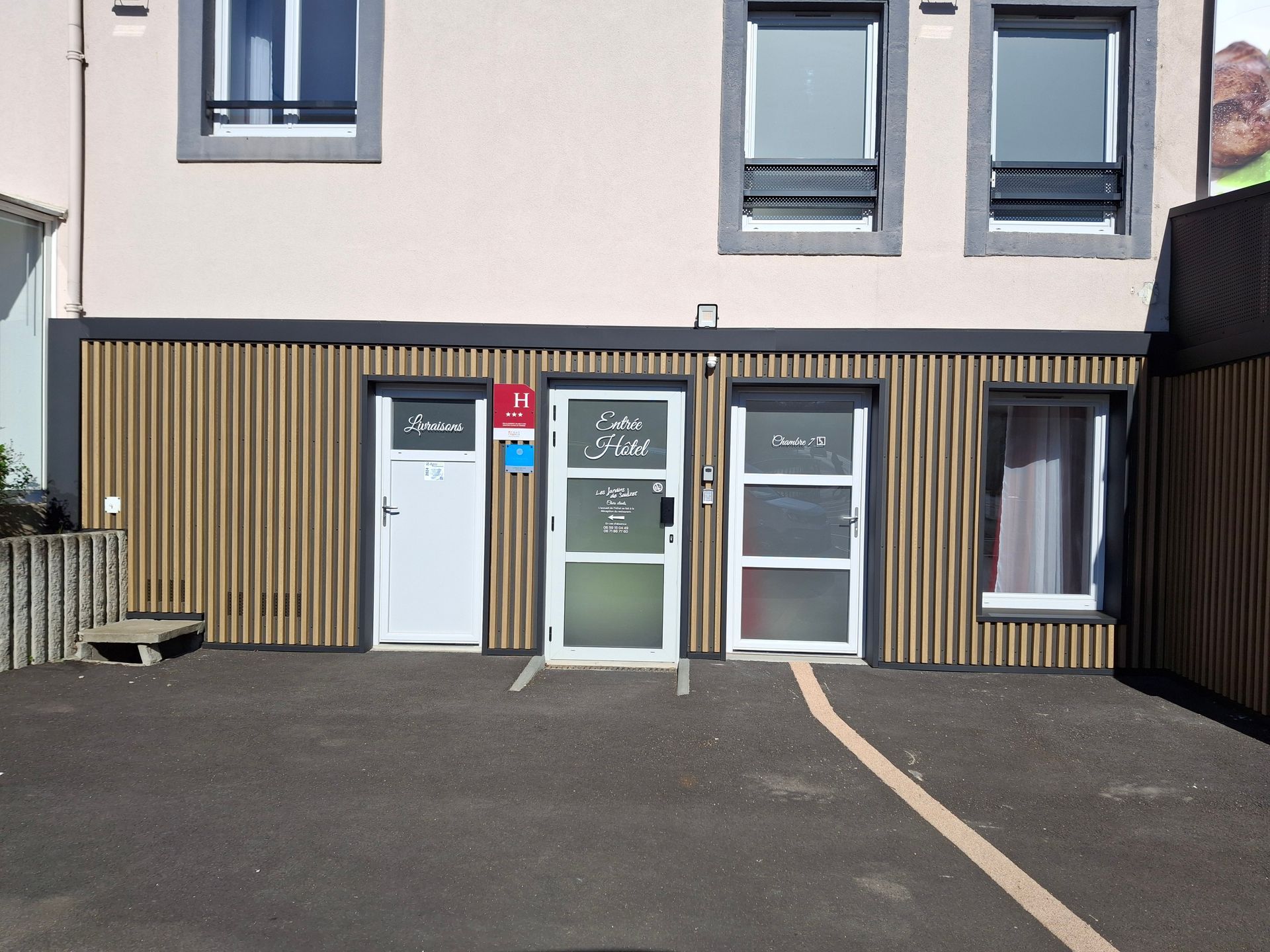 Extérieur d'un bâtiment à trois portes : blanche, vitrée et blanche.