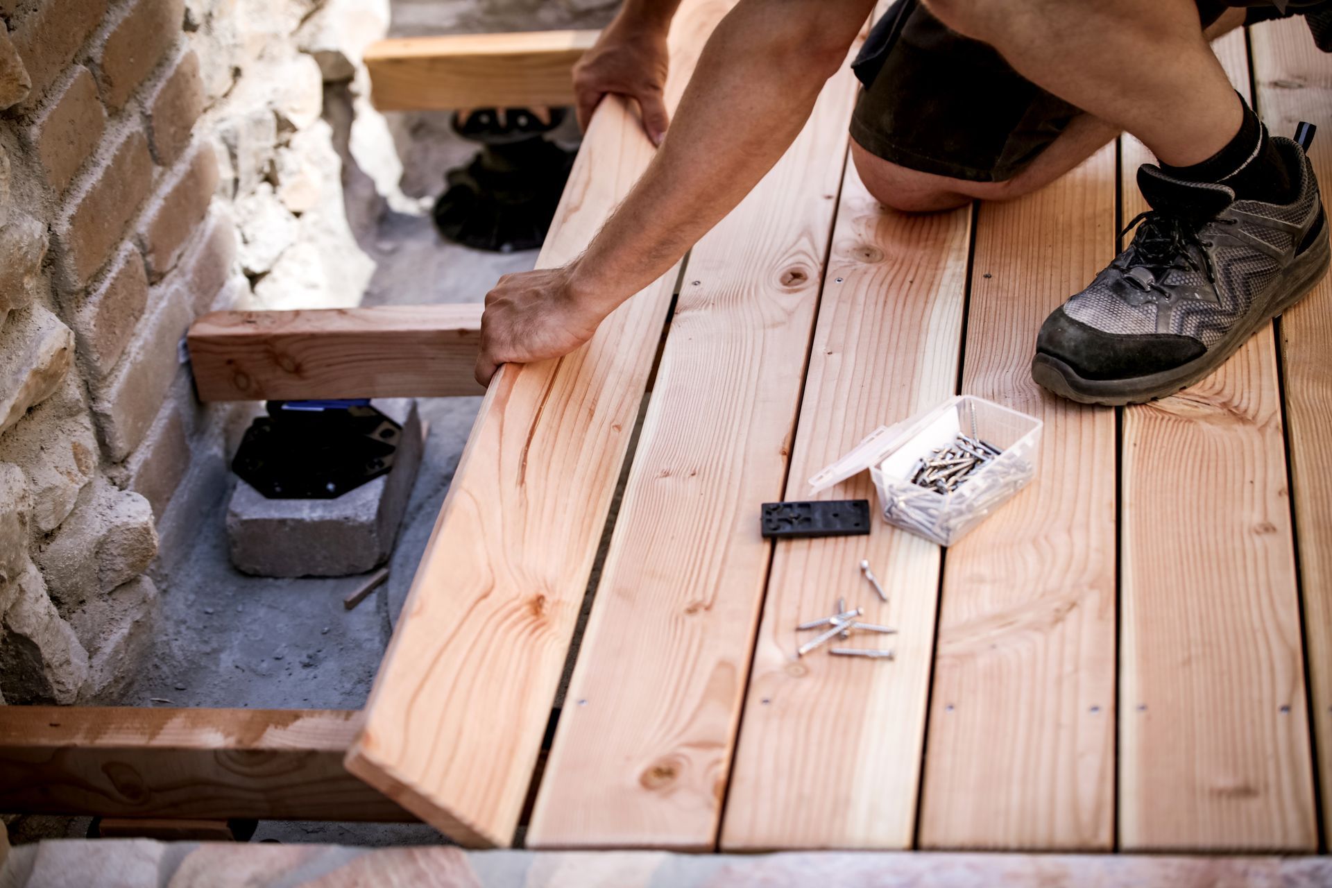 Un homme installe des planches de terrasse en bois.