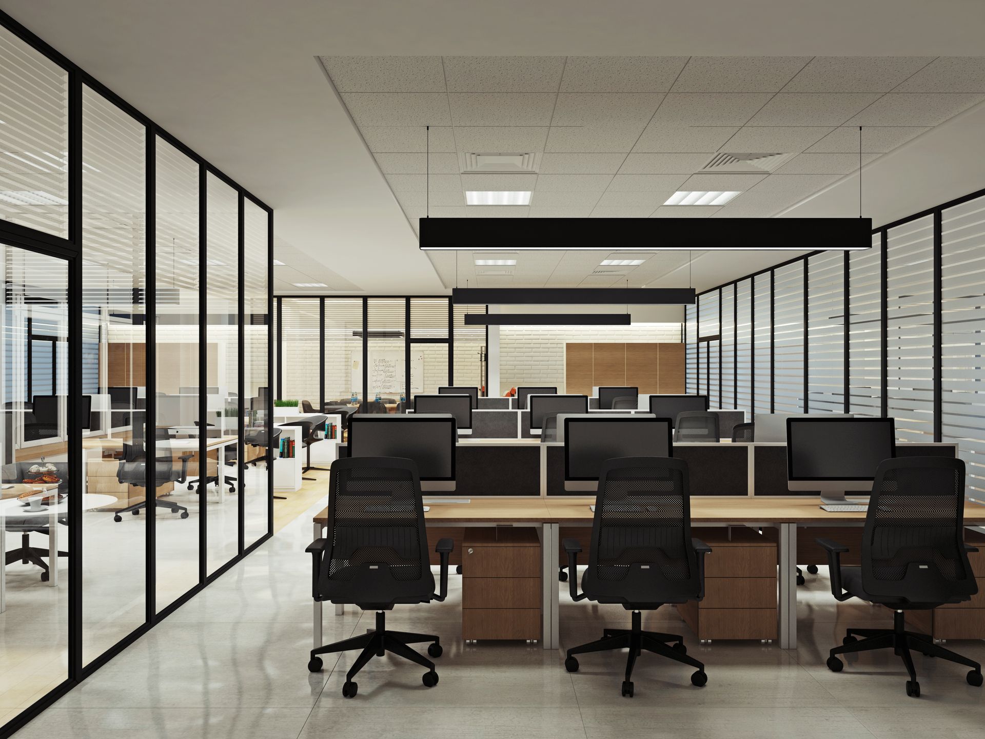 Bureau moderne avec rangées de bureaux, chaises et ordinateurs. Cloisons vitrées et éclairage vif.