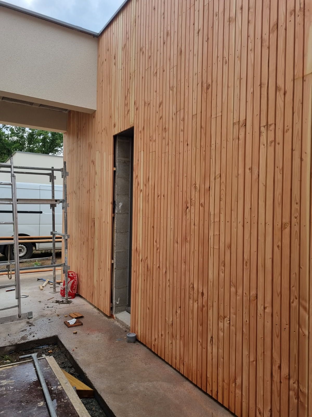 Bardage en bois sur la façade d'un bâtiment, avec une porte.