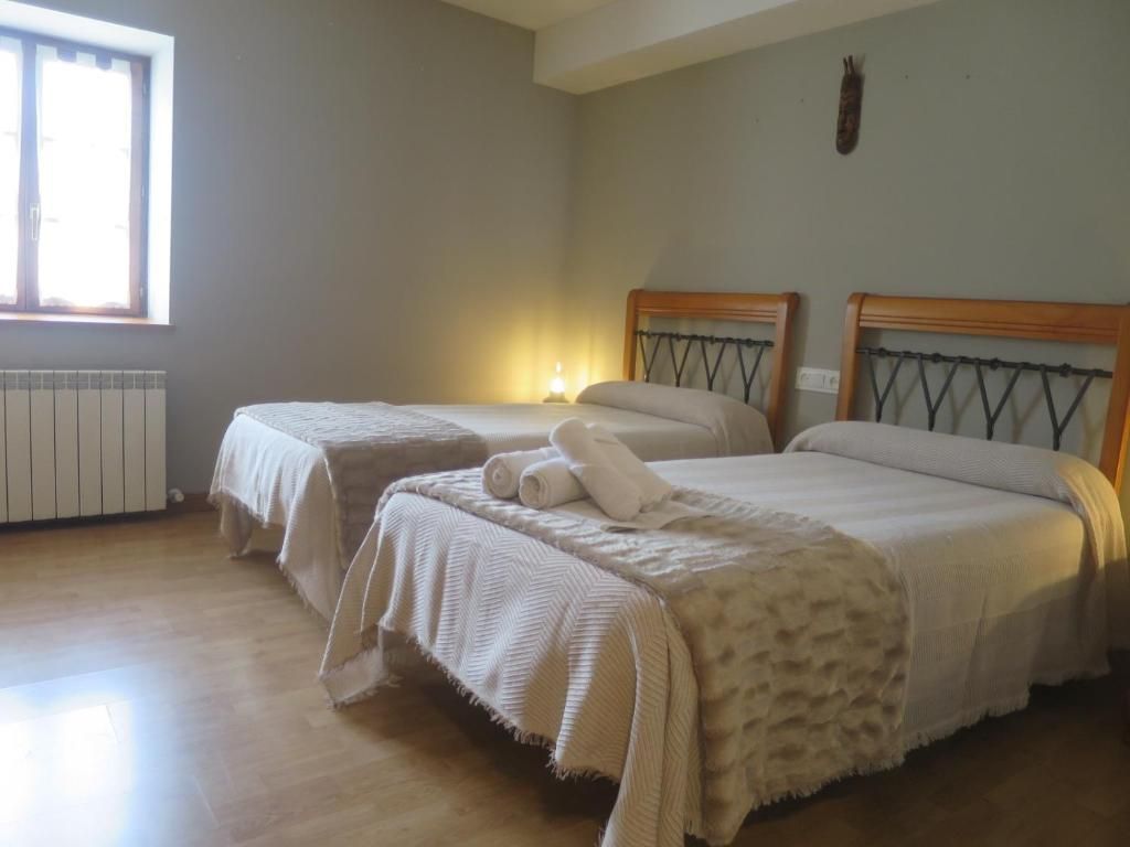 Dos camas individuales en una habitación de paredes grises con cabeceros de madera. Toallas blancas dobladas en una cama.