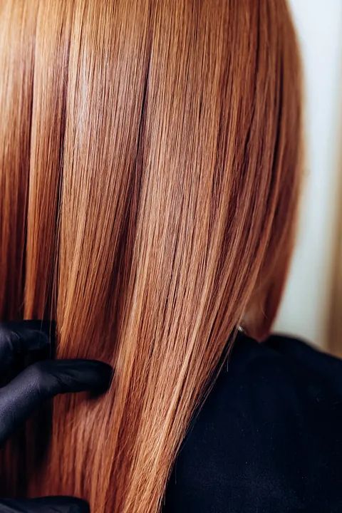 Una mujer se está alisando el cabello en la peluquería.
