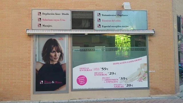 El frente de una peluquería con una foto de una mujer en la ventana.