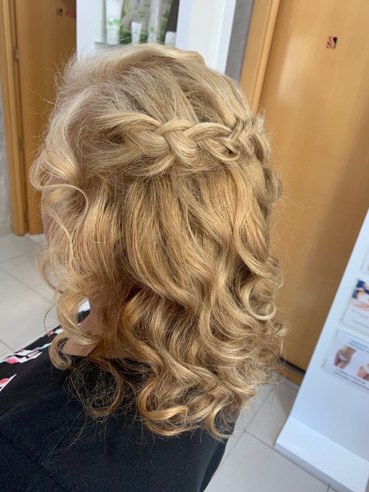 Una mujer con cabello rubio está sentada en una silla con el cabello recogido en una trenza.