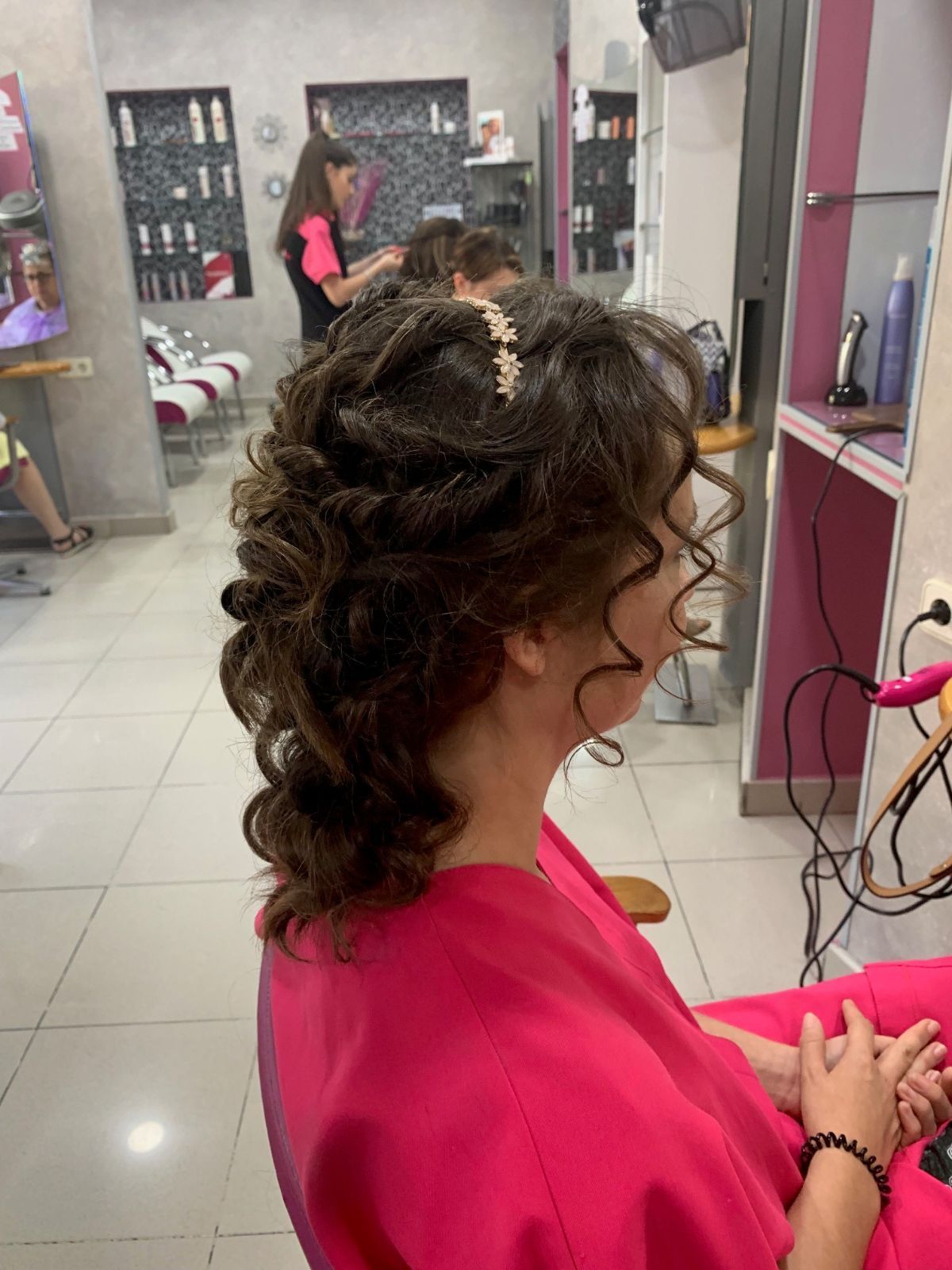 Una mujer con una bata rosa se está peinando en una peluquería.
