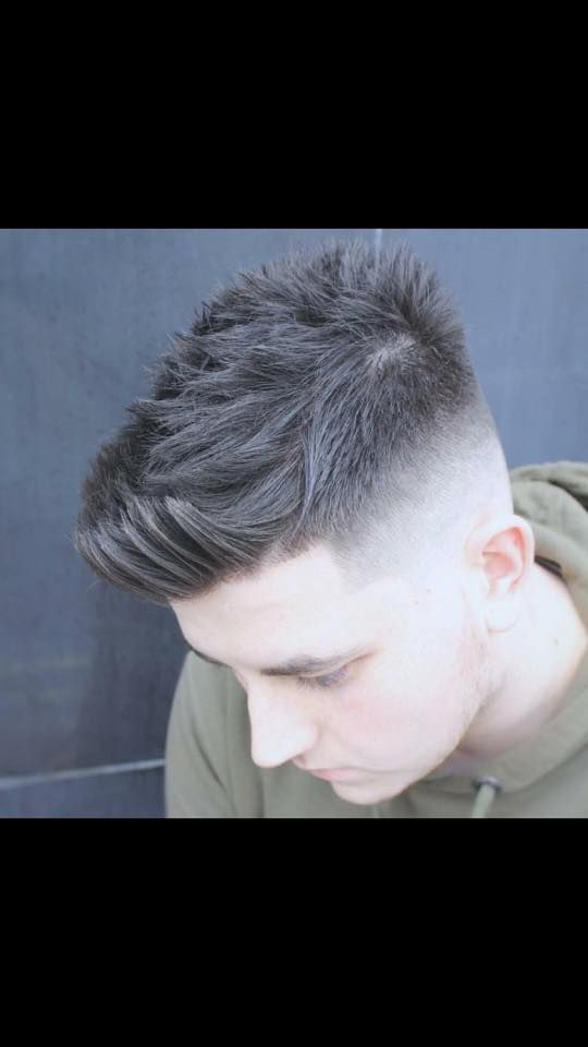 Un joven con un corte de pelo descolorido lleva una sudadera con capucha verde.