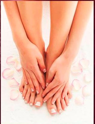 Un primer plano de las manos y los pies de una mujer con pétalos en el fondo.